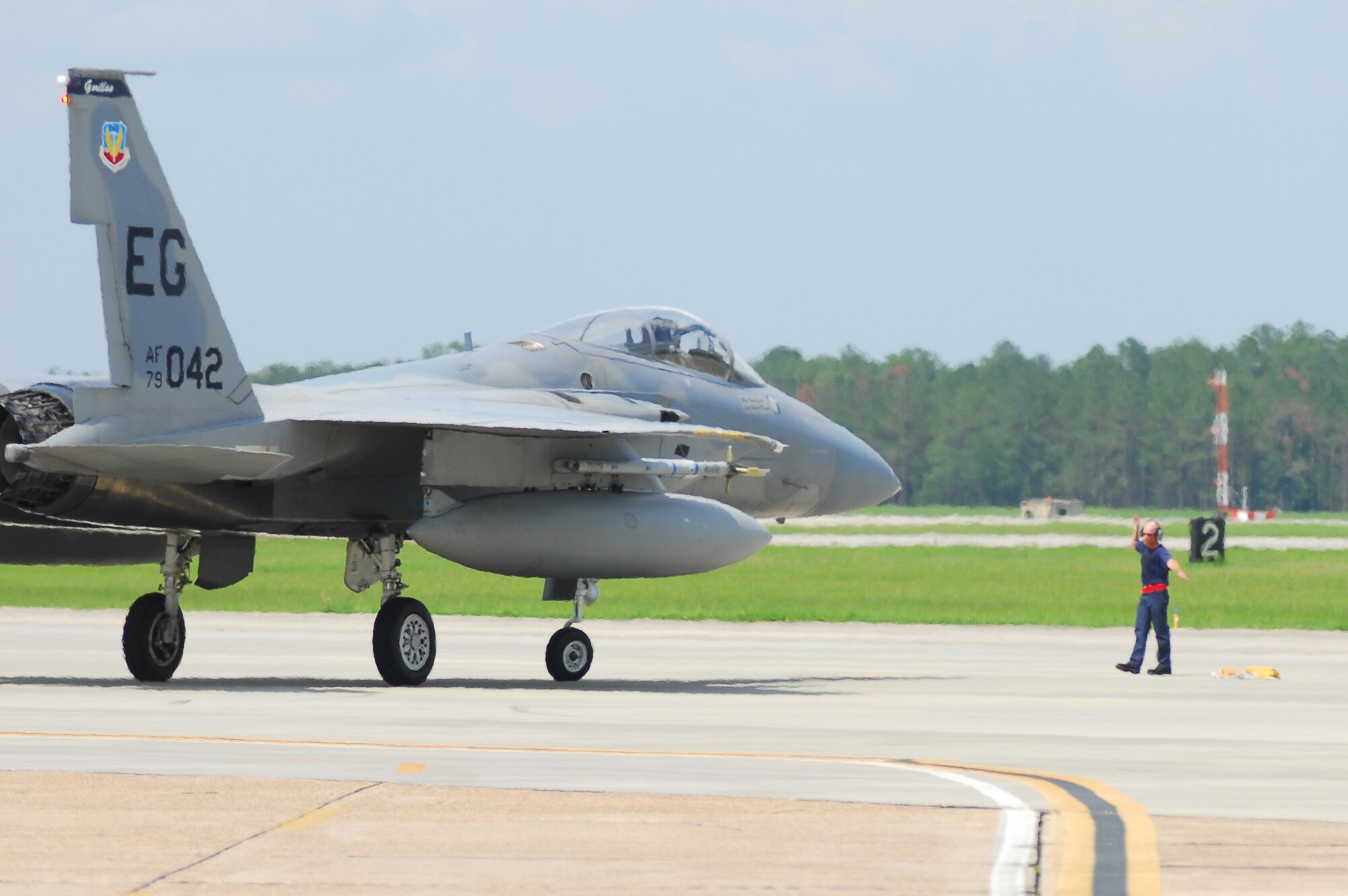 Tim Bourgeois, Defense Contract Services Incorporated transient alert technician, directs an arriving F-15 Eagle into a parking location July 2 at Moody Air Force Base, Ga. The aircraft was unable to land at Eglin AFB, Fla., its home station, due to severe weather. By the end of the day, 22 F-15’s were forced to divert to Moody, the largest number the base has ever received. (U.S. Air Force photo by Tech. Sgt. Parker Gyokeres)