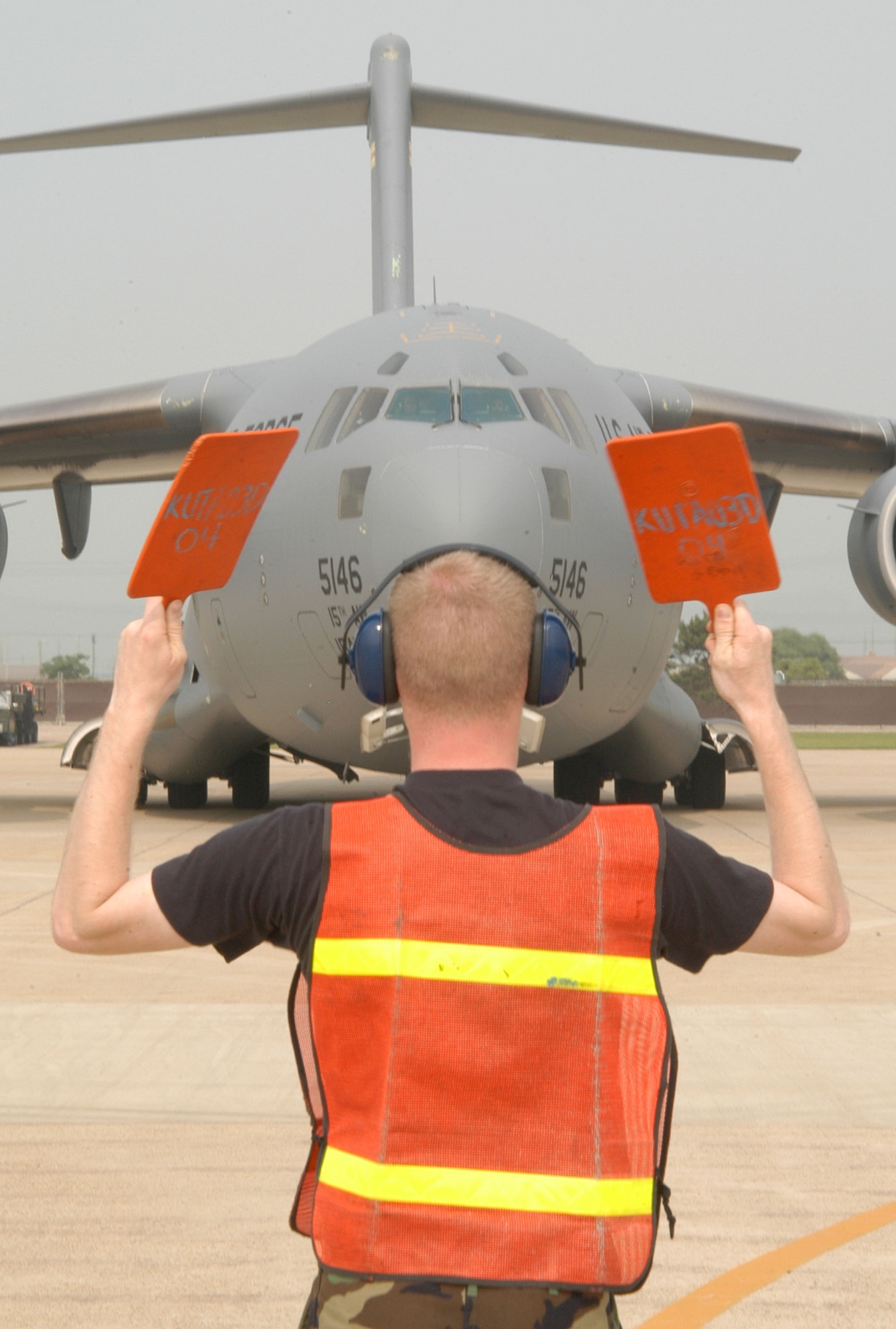 KUNSAN AIR BASE, Republic of Korea -- Senior Airman Korey Cornelis, 8th Maintenance Squadron transient alert/crash recovery specialist, marshals the "Spirit of Hawaii" into its parking spot July 8. The C-17 Globemaster III, assigned to Hickam Air Force Base, Hawaii, airlifted more than 40 maintainers and equipment  from the 555th Expeditionary Fighter Squadron "Triple Nickel" here as part of their air expeditionary force requirements. More than 10 F-16 Fighting Falcons assigned to the 555th EFS arrived July 7. (U.S. Air Force photo/Senior Airman Stephen Collier)                              