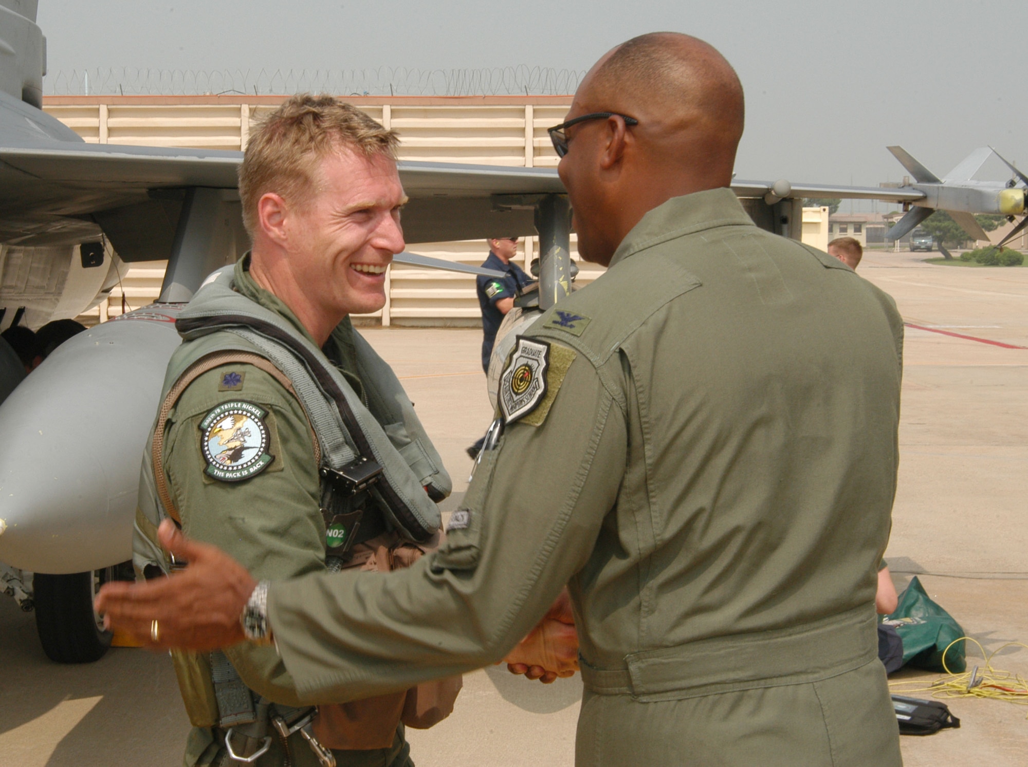 KUNSAN AIR BASE, Republic of Korea -- Lt. Col. Lance Landrum (left), 555th Expeditionary Fighter Squadron "Triple Nickel" pilot, greets Col. CQ "Wolf" Brown after exiting his F-16 Fighting Falcon July 7. Colonel Brown is the 8th Fighter Wing commander. More than 10 aircraft assigned to 555th EFS arrived here from Alaska after being hampered by poor weather conditions. The Triple Nickel is deployed to Kunsan as part of a force posture adjustment in the Northeast Asia region. (U.S. Air Force photo/Senior Airman Stephen Collier)