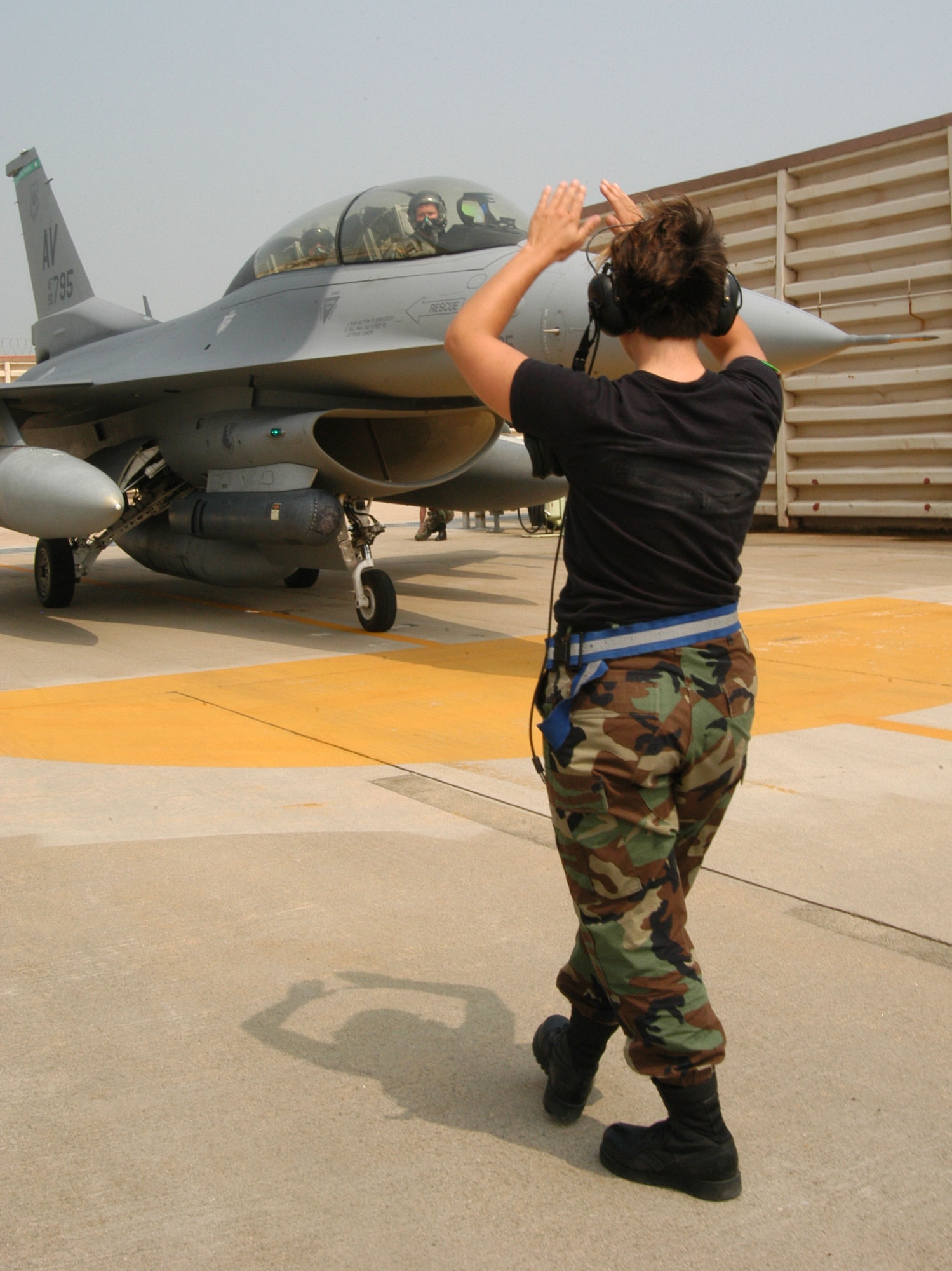 KUNSAN AIR BASE, Republic of Korea -- Senior Airman Kara Thornton, 555th Expeditionary Fighter Squadron assistant dedicated crew chief, marshals in a "Triple Nickel" F-16 Fighting Falcon from the squadron July 7. More than 10 aircraft assigned to 555th EFS arrived here from Alaska after being hampered by poor weather conditions. The Triple Nickel is deployed to Kunsan as part of a force posture adjustment in the Northeast Asia region. (U.S. Air Force photo/Senior Airman Stephen Collier)                                