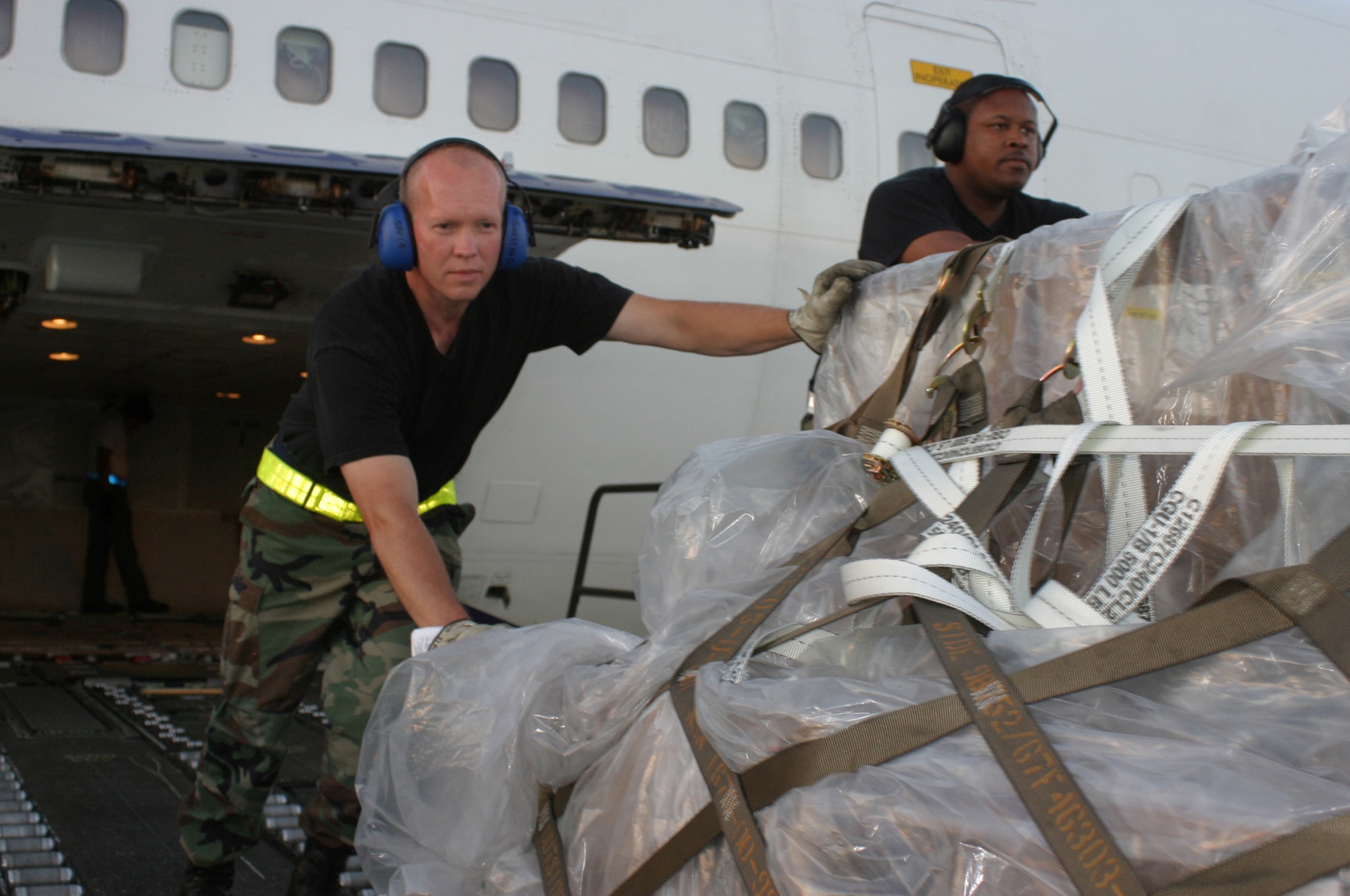 HICKAM AFB, Hawaii - Tech. Sgt. Brett Snelling and Airman 1st Class Starlain Thompson, ramp services specialist from the 87th Aerial Port Squadron deployed from Wright-Patterson AFB, Ohio unload cargo pallets from the lower cargo area of a 747 aircraft at Hickam AFB, Hawaii. (U.S. Air Force photo/Master Sgt. Doug Moore)