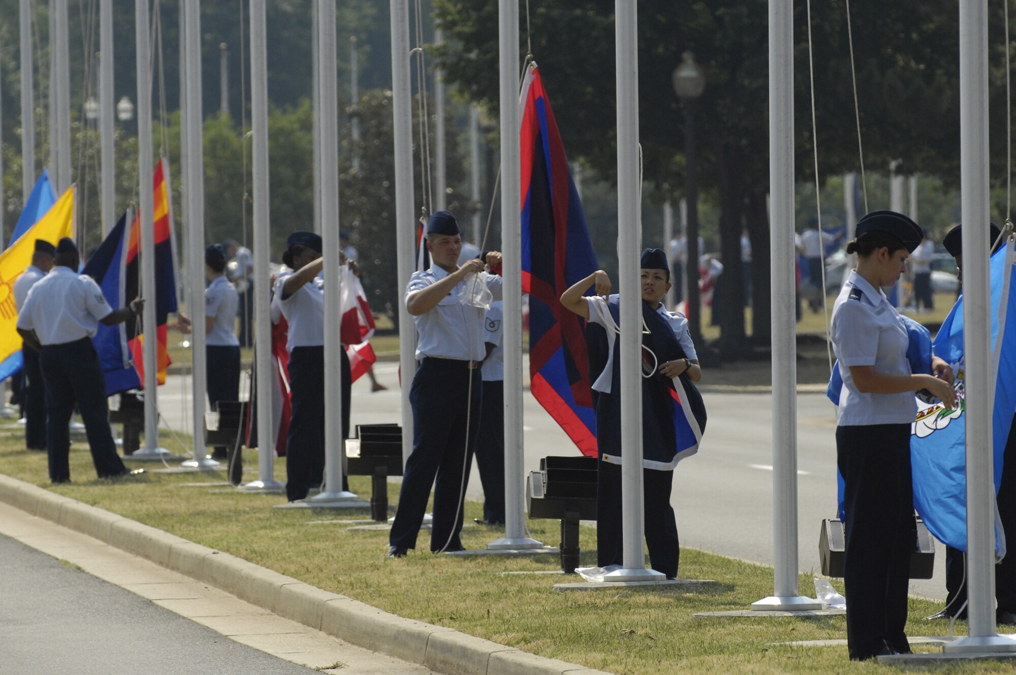 Airmen start raising their designated flags during a flag-raising ceremony July 9 as part of the Arnold Gate dedication at Bolling. Re-establishing Bolling’s Avenue of Flags, the ceremony involved the simultaneous rising of 56 different flags by members of the Bolling community representing the 50 states, as well the District of Columbia, Guam, Puerto Rico, American Samoa, Northern Marianna Islands and the U.S. Virgin Islands. (U.S. Air Force photo by Senior Airman Dan DeCook)
