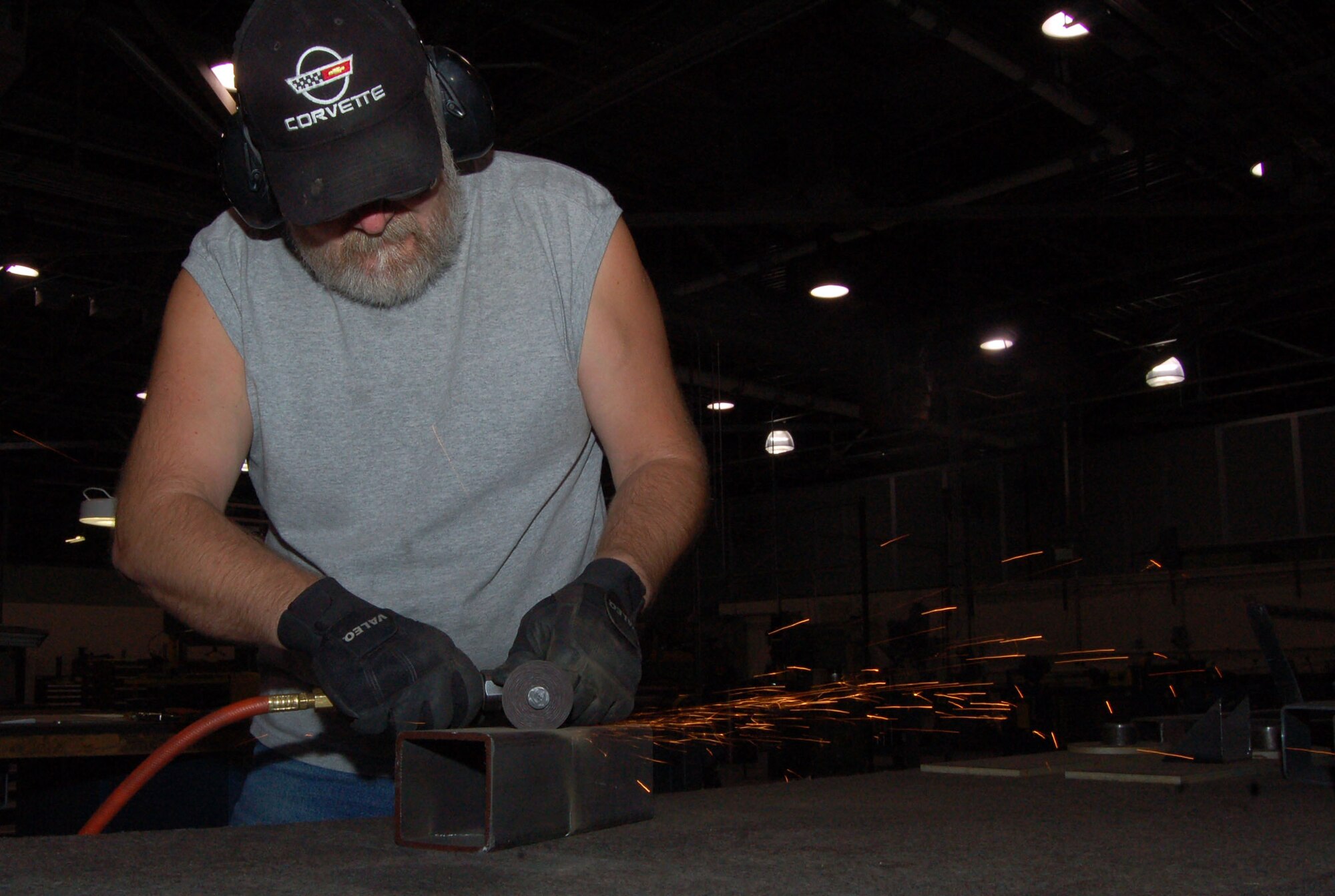 Augie Anderson, an aircraft structural mechanic with the 412th Maintenance Squadron, shapes a metal component with a pneumatic-powered cutting wheel. (Photo by Senior Airman Jason Hernandez)