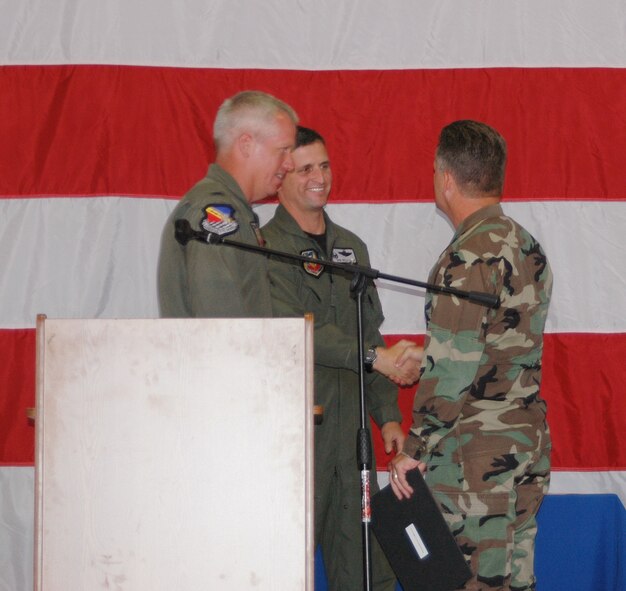Col. Robert Beletic shakes hands with Col. Scott Chambers, 75th Air Base Wing commander, at Col. Beletic's farewell in Hangar 37 June 29 while Col. Todd Harmer looks on.