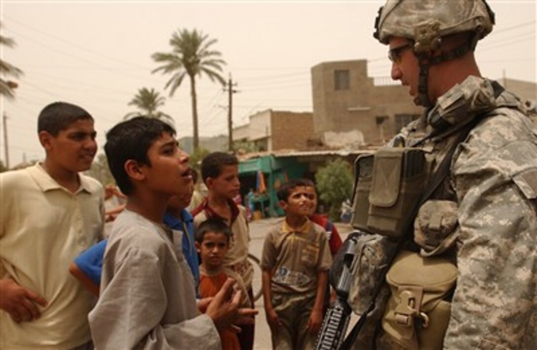 U.S. Army Staff Sgt. Daniel Barker, from Delta Company, 2nd Battalion, 12th Cavalry Regiment, 2nd Infantry Division, talks with local Iraqi children while on a foot patrol with his platoon through an open market in the Dora area of Baghdad, Iraq, July 8, 2007. 