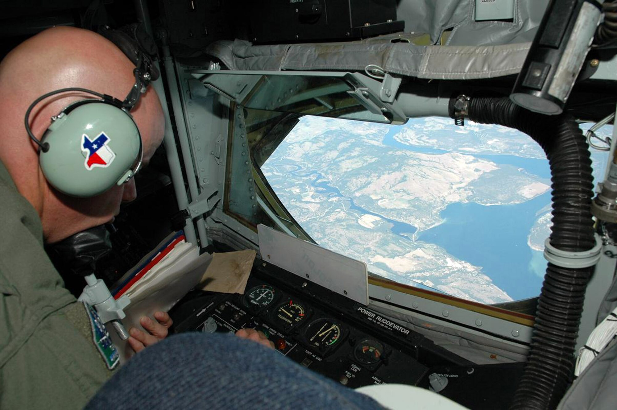 Master Sgt. Jim Pittman lies in the boom pod at the rear of a KC-135 Stratotanker where he can maneuver the refueling boom used to connect with receiving aircraft. Sergeant Pittman, a boom operator from the 92nd Air Refueling Wing at Fairchild Air Force Base, Wash., has a Texas symbol on his headset in honor of his mother's side of the family, which hails from the Lone Star state. (U.S. Air Force photo/1st Lt. Tristan Hinderliter)