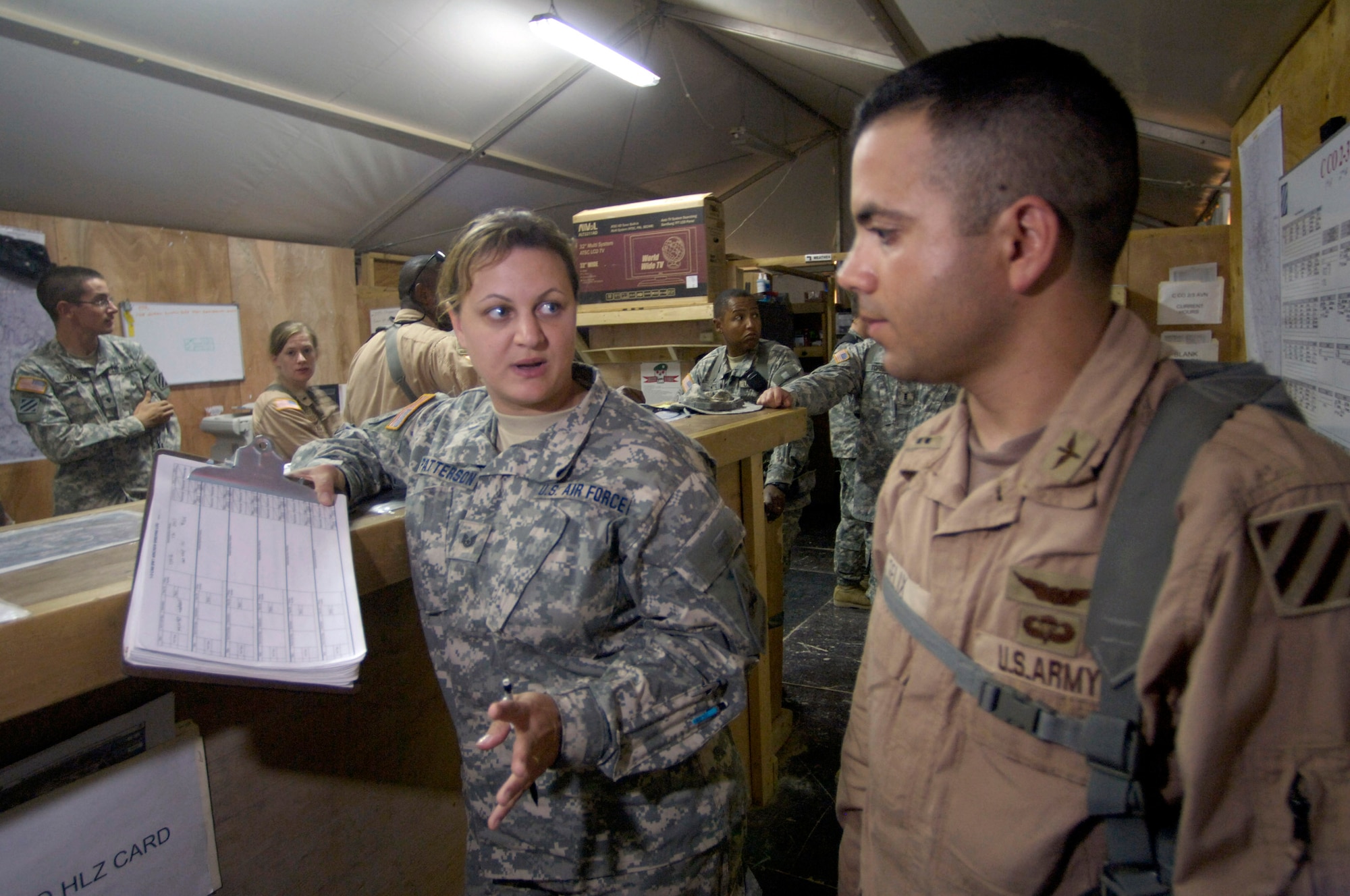 Tech. Sgt. Andrea Patterson (left) provides a weather brief in the 2nd Battalion, 3rd Combat Aviation Brigade, 3rd Infantry Division, tactical operations center to a UH-60 Blackhawk pilot prior to a medical evacuation mission June 23 at Forward Operating Base Kalsu, Iraq. Sergeant Patterson, and her fellow Air Force weather forecasters, provide 24 hour a day weather updates to the various U. S. Army 3rd Infantry Division's operations occurring in the Triangle of Death area. The instantaneous weather information the battlefield weathermen are able to provide are critical to the success, and to the safety of the 3rd ID's ground and aviation operations. Though Sergeant Patterson is attached to the 3rd ID, she officially falls under the recently formed 3rd Expeditionary Weather Squadron headquartered on Camp Victory in Iraq. She is deployed from Detachment 6 of the 7th Weather Squadron from Wiesbaden, Germany. (U.S. Air Force photo/Master Sgt. Jim Varhegyi) 

