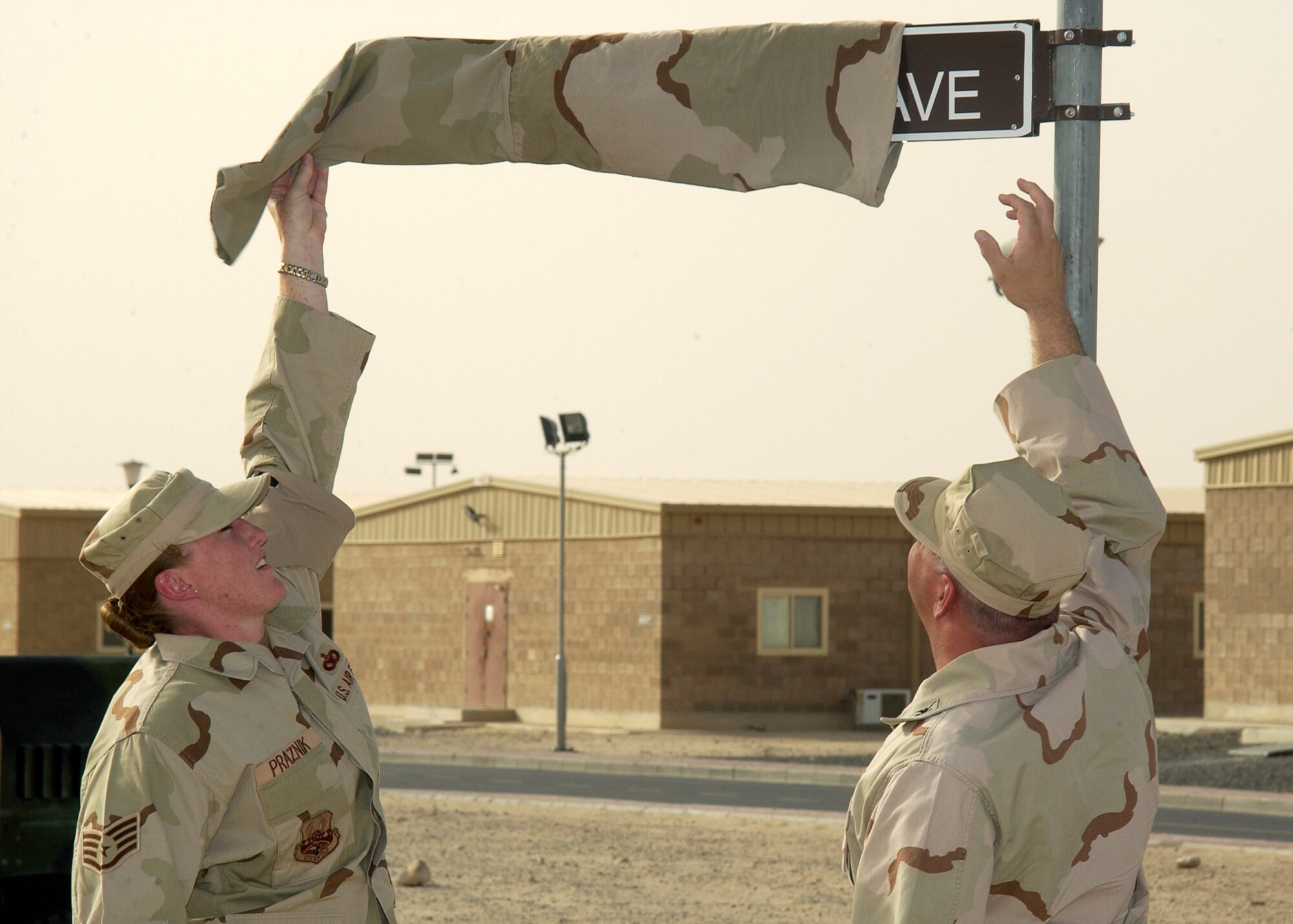 SOUTHWEST ASIA -- Staff. Sgt. Tracy Praznik, 386th Expeditionary Security Forces Squadron operations support NCOIC, and Col. Paul Curlett, 386th Air Expeditionary Wing outgoing commander, remove a covering from the street sign for Ware Ave. The street was named after Airman 1st Class Carl Ware, who was killed in a non-combat-related incident in July of 2006. (U.S. Air Force photo by Senior Airman Andrew Dumboski)