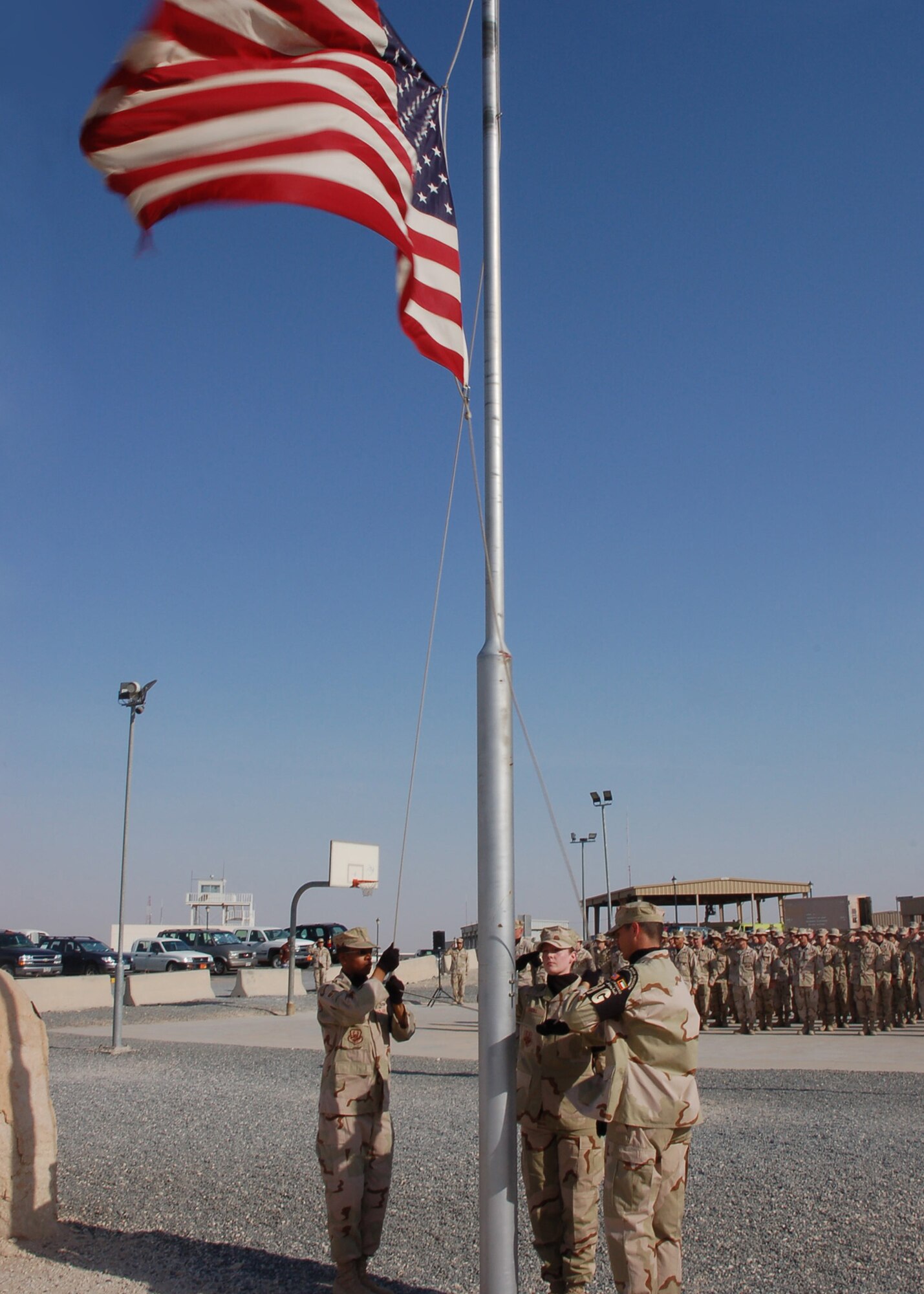 SOUTHWEST ASIA -- Members of the 386th Air Expeditionary Wing look on in formation while an Honor Guard team lowers the flag during retreat July 4. Immediately following the ceremony, the flag was taken to the site of Ware Memorial to witness its dedication. After the dedication, the flag was sent to Airman 1st Class Carl Ware Jr.'s family. Airman Ware was killed in a non-combat related incident in July of 2006. (U.S. Air Force photo by Staff. Sgt. Raymond Mills)