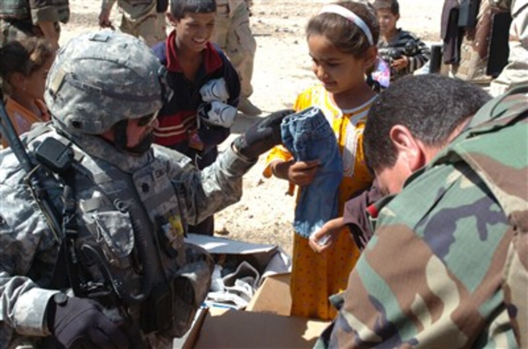 U.S. Army Lt. Col. Guy Edmondson (left) hands out clothing to village children in Mosul, Iraq, on June 20, 2007.  