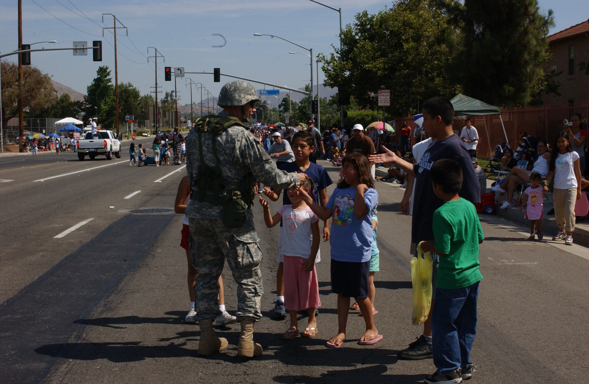 Col. Gregory Maida, the 304th Sustainment Brigade commander hands out Army pencils to kids lining the street during the parade through Moreno Valley.  The Air Force, Army and Navy Reserve as well as the Air National Guard participated in the parade.  (photo by U.S. Army Specialist Tracy Ellingsen)
