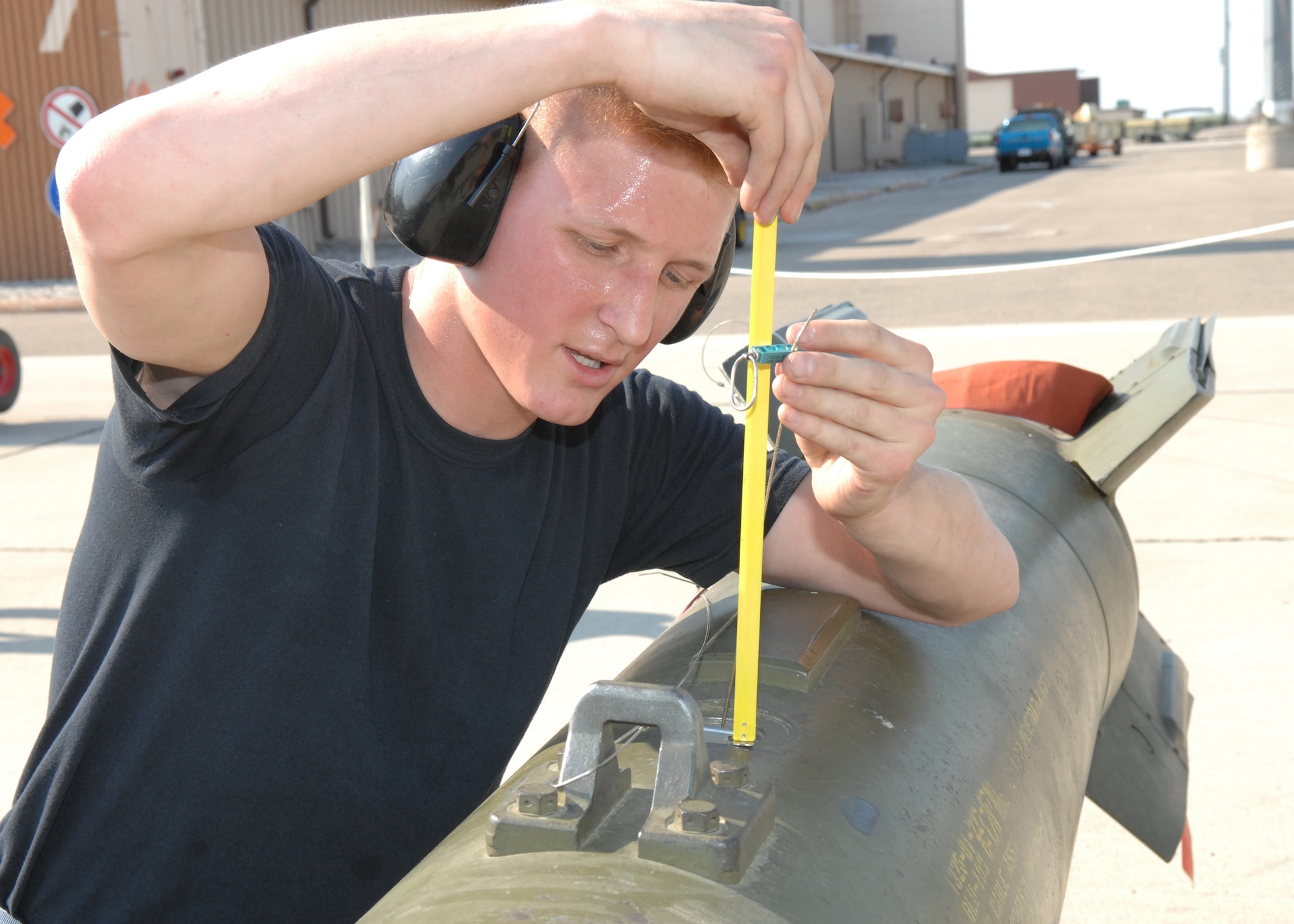 Airman 1st Class  Jacob Johnson, 8th Aircraft Maintenance Unit, measures the fuse arming wire lanyard; this will be retained by the MAU-12 bomb rack when the bomb is released arming the fuse and bomb for detonation during the competition.  (U.S. Air Force photo by Senior Airman Anthony Nelson Jr.)
