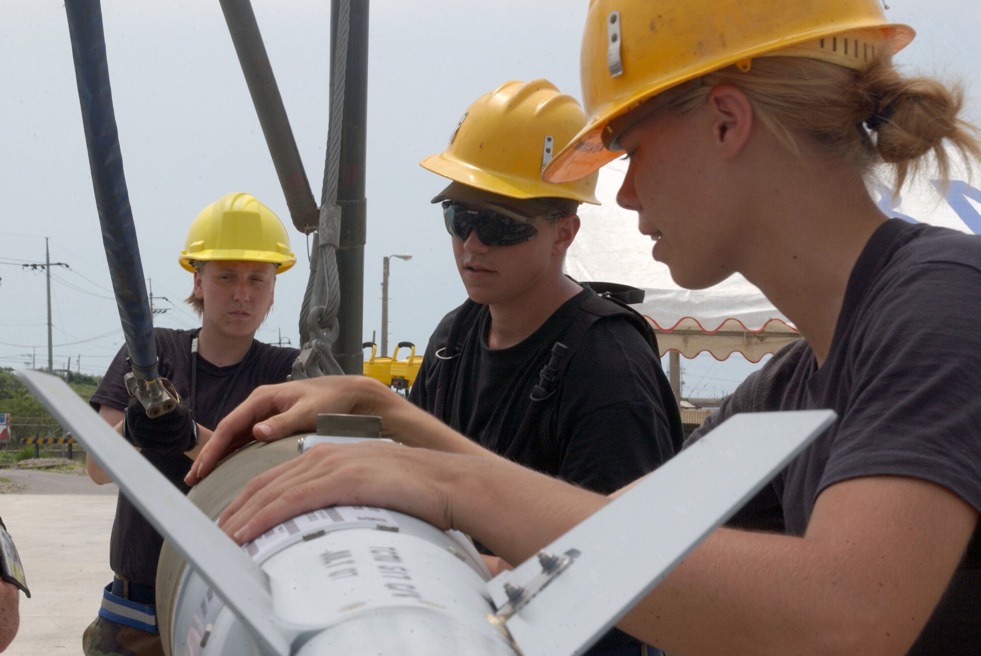 Senior Airman Natalie Huntington (left) and Senior Airman Thomas Newell from Osan Air Base, South Korea, along with Airman 1st Class Stephanie Nelson, from Aviano Air Base Italy, team together to remove a bomb from a trailer July 11 during a combat ammunition production exercise being held at Kunsan AB, South Korea.  The three-day exercise provides Pacific Air Forces and Air Combat Command units with training in mass munitions assembly in support of aircraft sortie generation.  (U.S. Air Force photo/Senior Steven R. Doty) 
