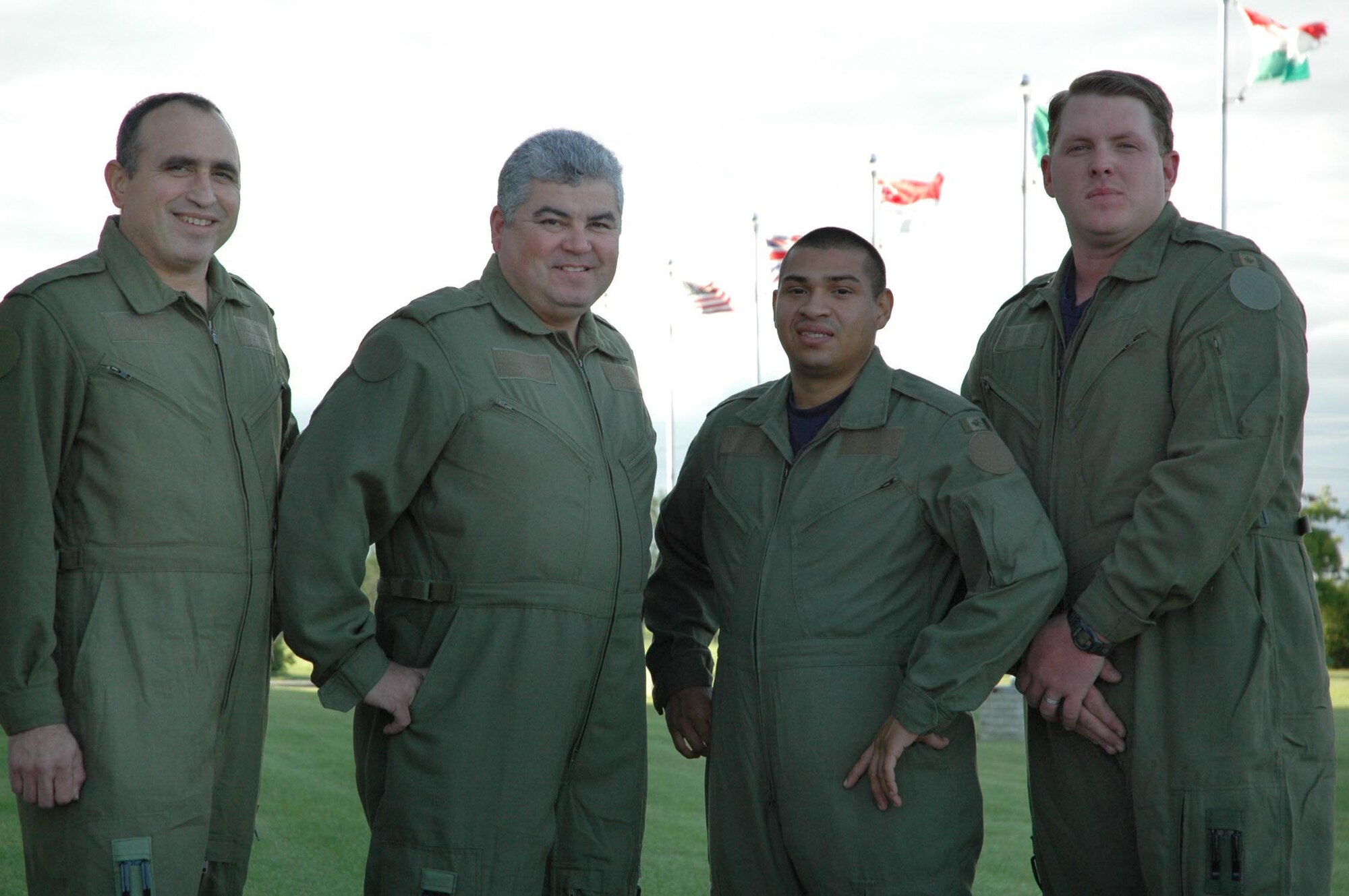 Country flags fly above the heads of civil engineer squadron members (L-R) Senior Airman Albert Champion, Staff Sgt. Otto Adkins, Senior Airman David Luna and Staff Sgt. Cole Martin wearing flight suits in preparation for incentive rides. (USAF Photo/Senior Master Sgt. Marcus Falleaf)