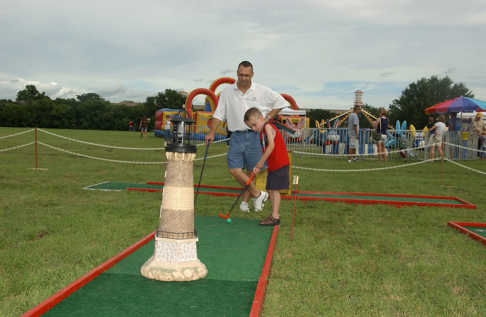 Capt. Jeff Nagy, Air Force Information Operations Center, observes his son's technique during a friendly putt putt golf challenge. Four-year-old Jordan was among the numerous Team Lackland youths who enjoyed some family time with their parents during the July 4 celebration at Lackland Air Force Base, Texas. (USAF photo by Alan Boedeker)                                