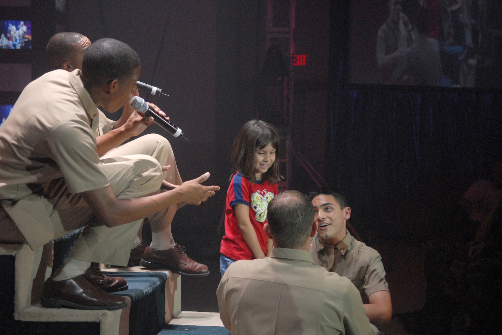 Tops In Blue fellows serenade 6-year-old Brianna Figueroa during a free concert July 4 at Bob Hope Performing Arts Center on Lackland Air Force Base, Texas. The performance was moved indoors due to inclement weather. Brianna is the daughter of Tech. Sgt. Ernesto Figueroa from the Inter-American Air Forces Academy. (USAF photo by Alan Boedeker)
