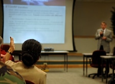 U.S. Navy Capt. Paz Gomez from the installation and environmental office of the secretary of defense asks Don Hill, operations manager for naval munitions at the Naval Weapons Station, S.C., a question regarding the supply for munitions at the joint basing table top exercise Tuesday for the anticipated joint basing with Charleston AFB, S.C., and Charleston Naval Weapons Station, S.C.   (U.S. Air Force Photo/Airman 1st Class Nicholas Pilch)