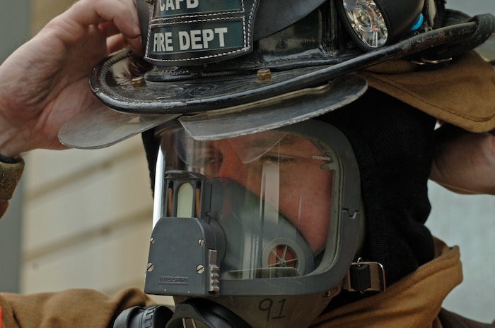 Tech. Sgt. John Hearn, 437th Civil Engineer Squadron firefighter, puts his helmet on prior to fighting the fire at a training exercise May 23 at the Charleston AFB fire department training facility. (U.S. Air Force photo/Staff Sgt. April Quintanilla)