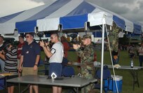 Airmen Cecil Brett, Survival, Evasion, Resistance and Escape training student, left, and Nicholas Burns, Airborne Maintenance, test their marksmanship at a paintball booth July 4 during holiday festivities at Lackland Air Force Base, Texas. (USAF photo by Alan Boedeker)                               