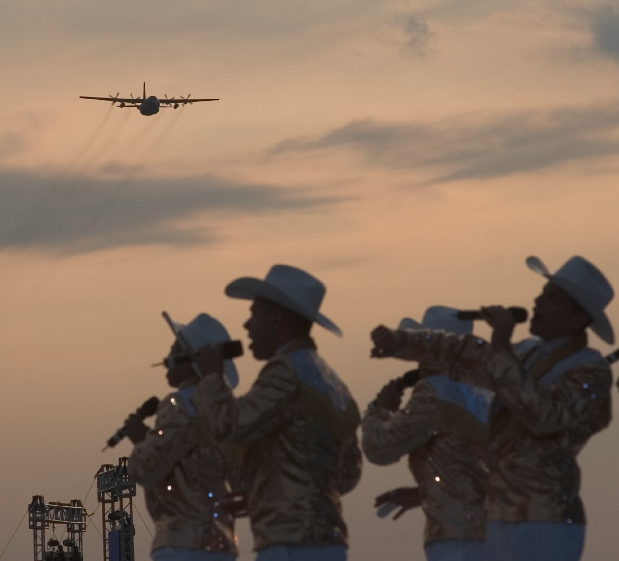 A C-130 Hercules approaches as members of the U.S. Air Force Tops in Blue entertainment troupe perform at the Air Force Materiel Command Tattoo ceremony at Wright-Patterson Air Force Base June 29.  A crowd of more than 60,000 from southwest Ohio, eastern Indiana and northen Kentucky were treated to patriotic music, aircraft flyovers and fireworks during the 60th Anniversary of the U.S. Air Force commemorative event. (Spencer P. Lane/U.S. Air Force)