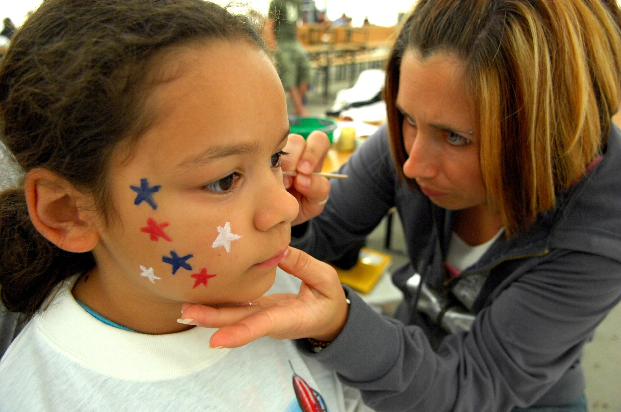 Michelle Mastrorocco, 31st Services Squadron Aviano Youth Programs, paints Riley Holzworth’s face during the Aviano Fourth of July festivities held in Freedom Park.
There were many family activities, including a youth scavenger hunt, bouncy castles, games  and food and beverage booths.
 (U.S. Air Force photos by Staff Sgt. Michael Holzworth)