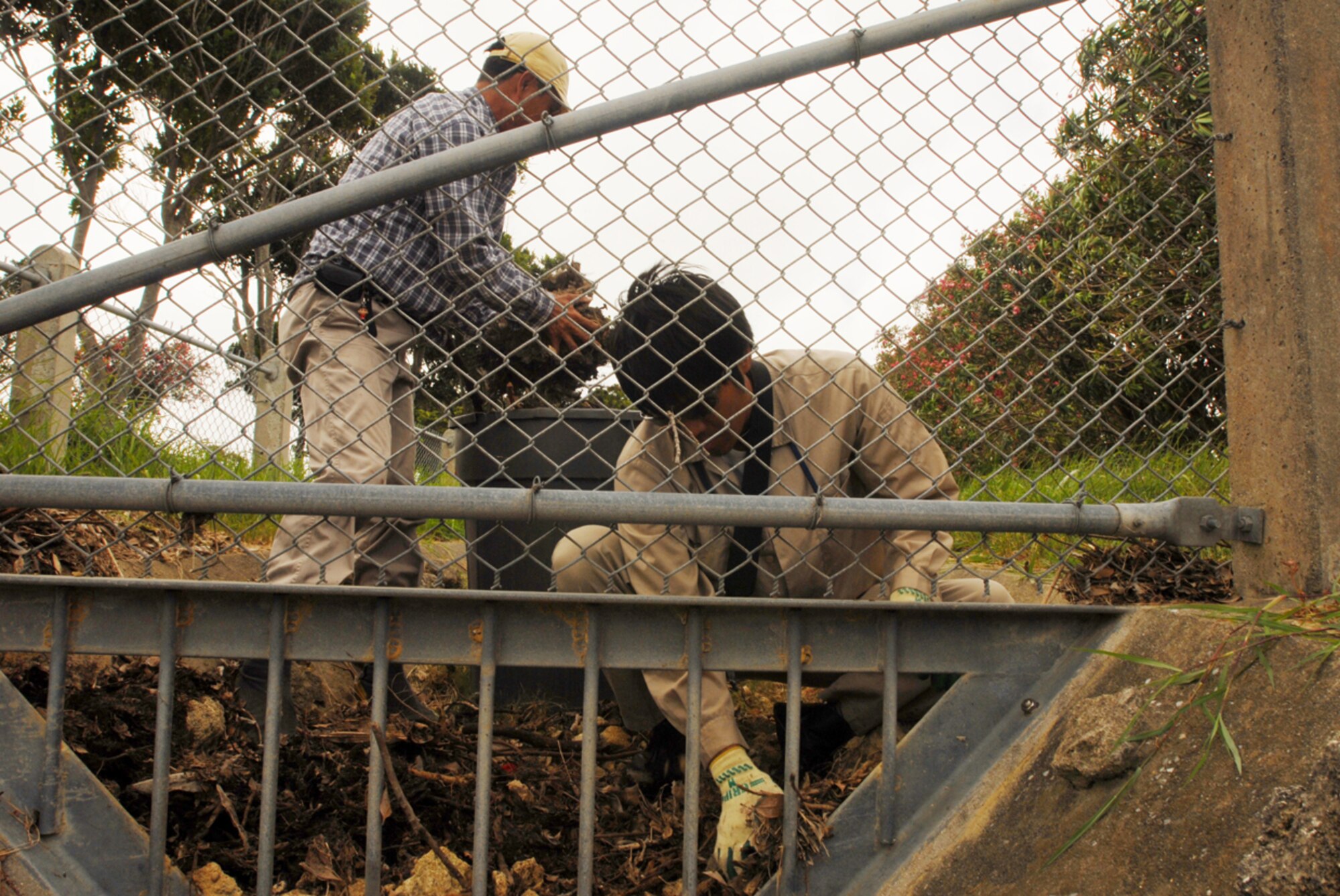 Atushi Matayoshi and Nobunuki Higa clear debris from amain drain for the airfield at Kadena Air Base, Japan on July 12, 2007. The drain is being cleared in preparation of Typhoon Man-Yi, the first typhoon of the year for the base. Mr Matayoshi and Mr Higa are assigned to the ground maintenance section of the 18th Civil Engineer Squadron. U.S. Air Force photo/Staff Sgt. Chrissy FitzGerald