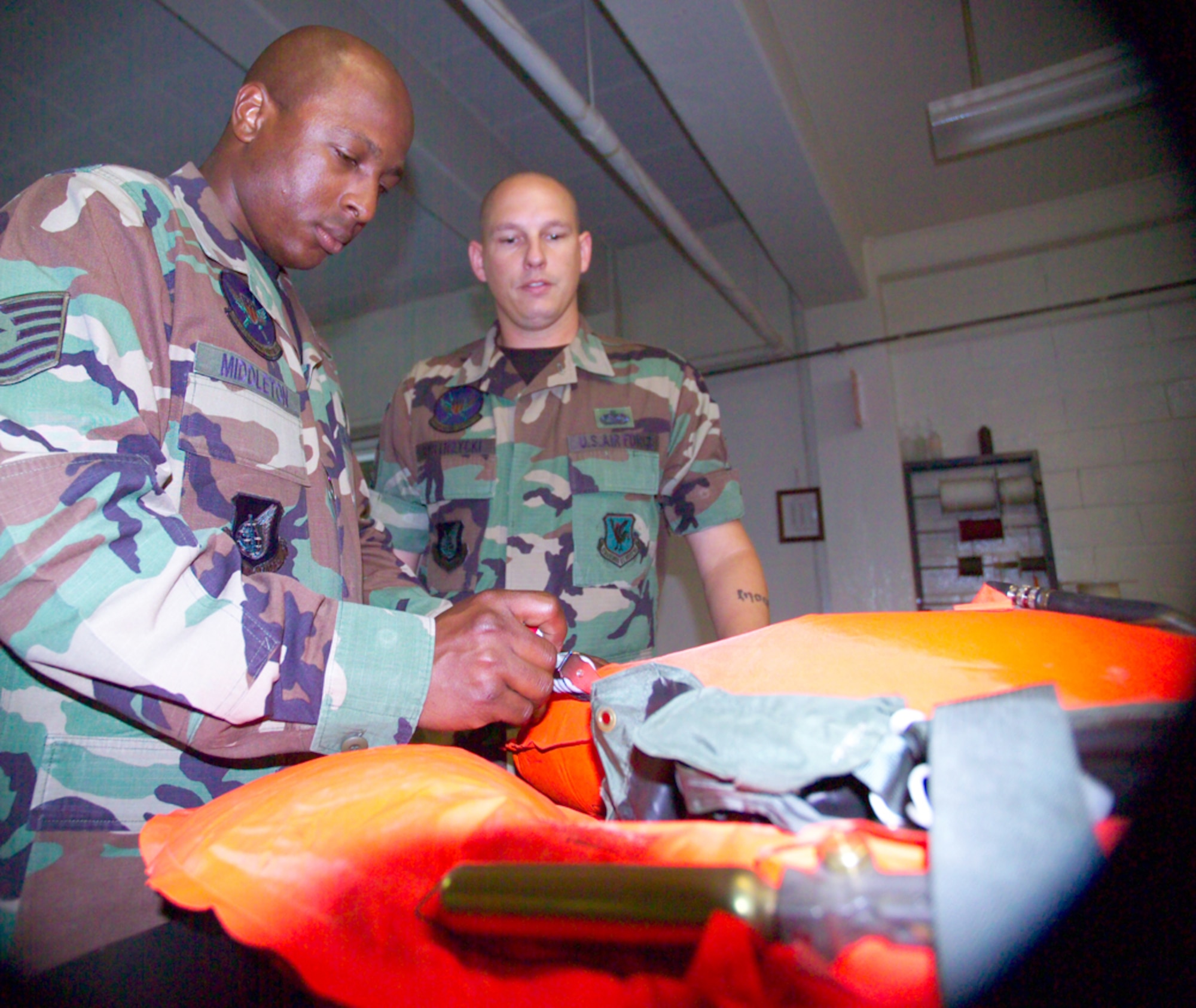 Staff Sgt. Richard Bystrzycki, right, shows Tech. Sgt. Timothy Middleton, left, maintenance procedures on a life preserver unit during cross training into the new aircrew flight equipment career field at the 18th Operations Squadron Kadena Air Base, Japan. U.S. Air Force/Scott Hallford