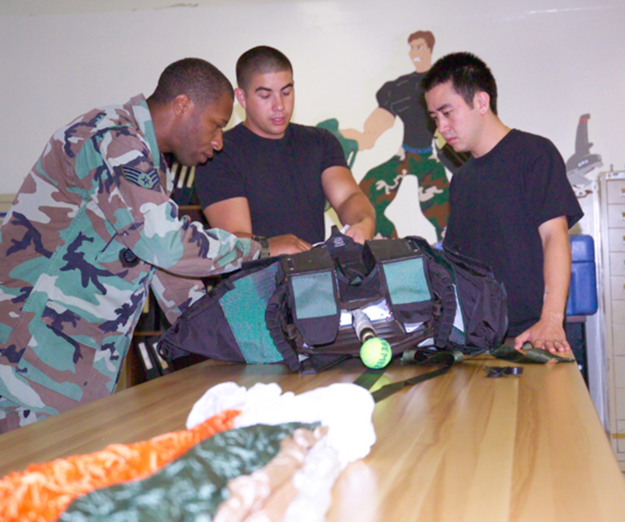 Tech. Sgt. Thomas Canada, Senior Airman Adam Miranda and Staff Sgt. John Pulley go over packing a parachute as part of cross utilization training at the 18th Operations Support Squadron's Aircrew Equipment Flight Kadena Air Base, Japan. Sergeants Canada and Pulley are life support trained, while Airman Miranda is survival equipment trained. 
U.S. Air Force/Scott Hallford