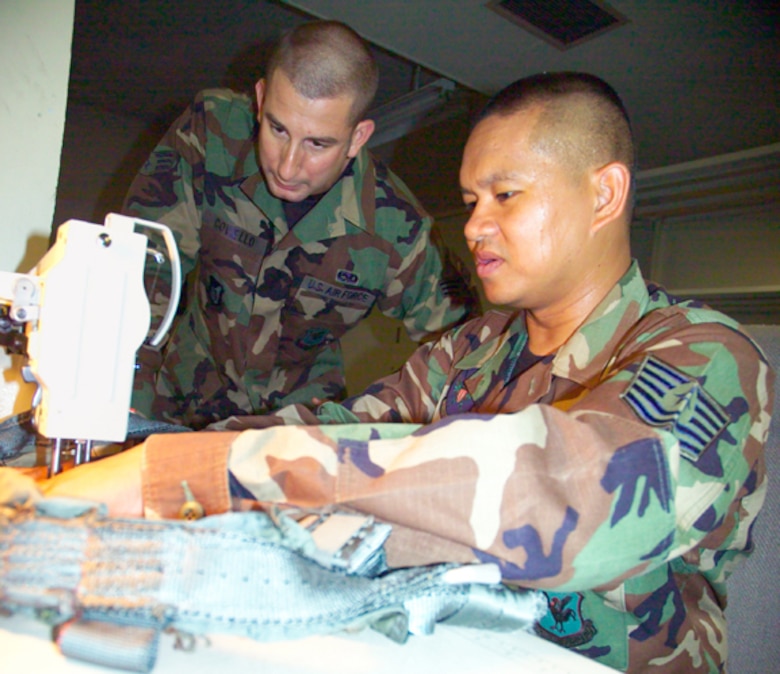 Airman 1st Class Robert Coviello teaches Tech. Sgt. Calvin Warner, Aircrew Flight Equipment Flight, sewing techniques on a harness at Kadena Air Base, Japan. The instruction is part of cross utilization training to merge aircrew life support and survival equipment into a new Air Force specialty code, aircrew flight equipment.
U.S. Air Force photo/Scott Hallford