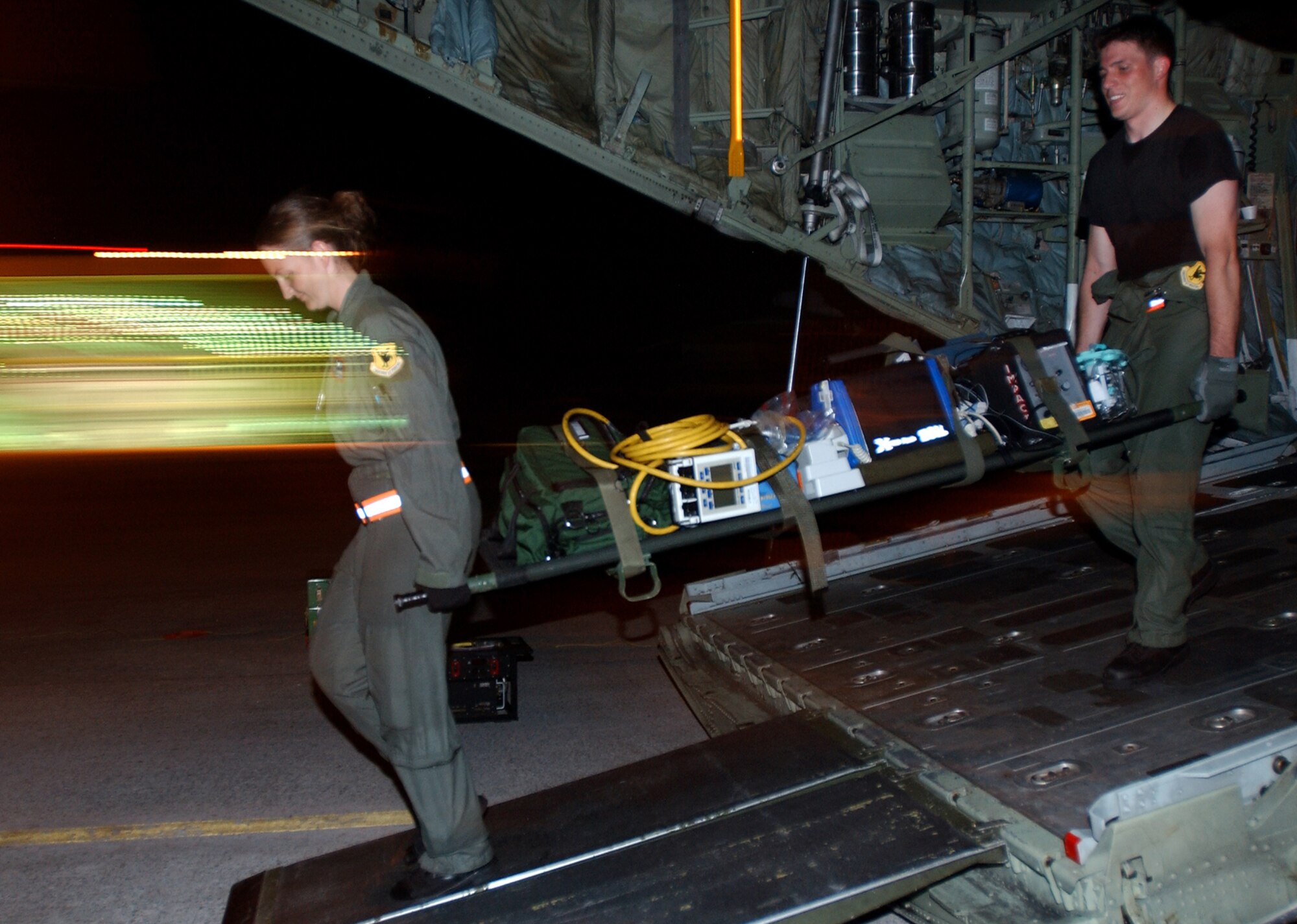 Staff Sgt. Erin Reifer and Senior Airman Kiley Gervitsen from the 18th Aeromedical Evacuation Squadron, Kadena Air Base, Japan, simulate evacuating casualties from a C-130 Hercules in Marine Corps Air Station Futenma, Japan, in preparation for Air Mobility Rodeo 2007. The unit practiced in the evenings to simulate night time operations for wartime missions. U.S. Air Force photo/Staff Sgt. Reynaldo Ramon