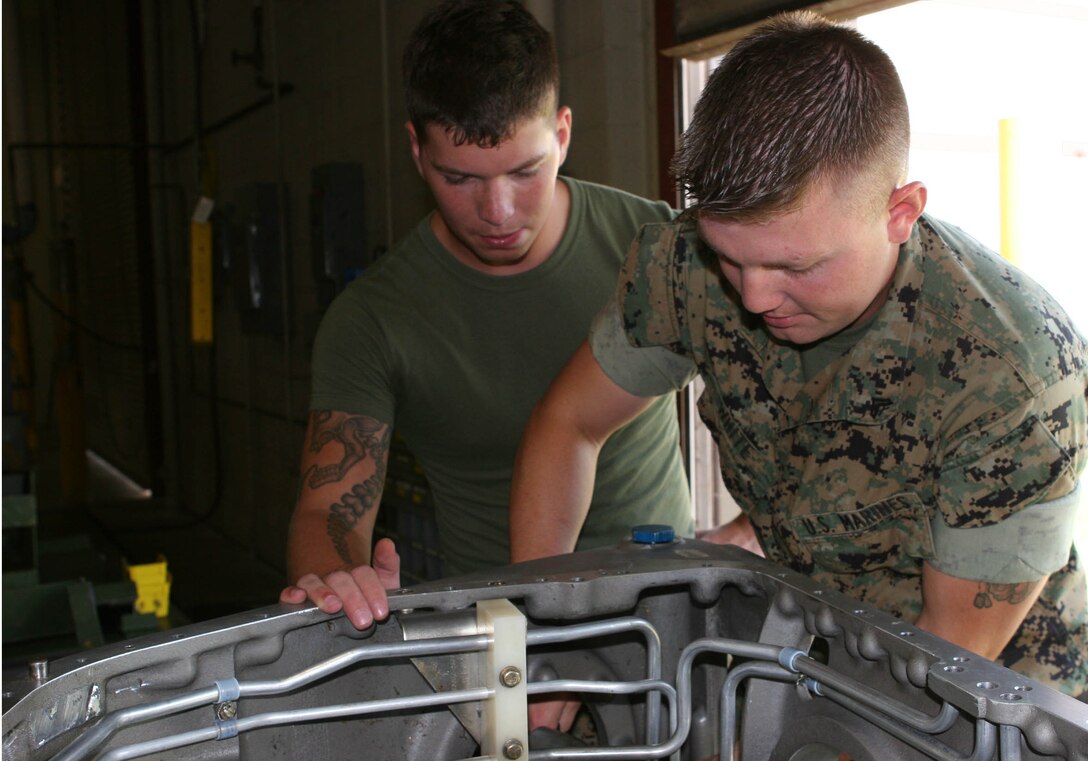 Cpl. Matthew D. White and Lance Cpl. Matthew C. Miller install oil tubes on an amphibious assault vehicle transmission.  Once repaired, the transmission will be installed into the AAV, then returned to its unit.  White and Miller are vehicle mechanics with General Support Maintenance Company, 2nd Maintenance Battalion, 2nd Marine Logistics Group.