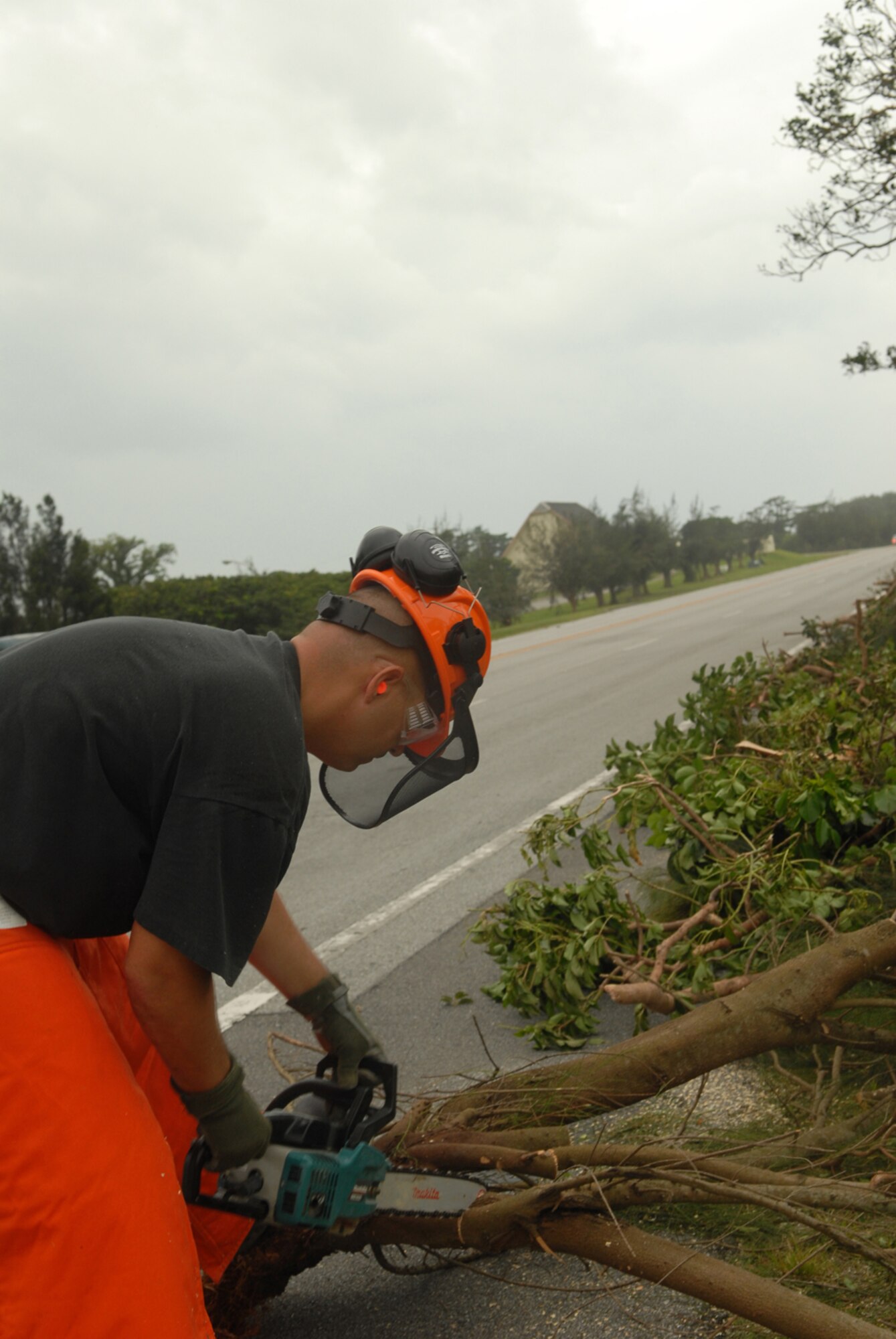 Tech. Sgt. John Platz cuts large downed branches with a chainsaw  at Kadena Air Base, Japan, July 14, 2007. The fallen branches were a result of Typhoon Man-Yi which brought the base 77 mph winds gusting to 105 mph.  There were no injuries or significant damages to base structures.  The typhoon was the strongest to hit the base since 2003.  Sergeant Platz is an equipment operator with the 18th Civil Engineer Squadron.  U.S. Air Force Photo/Staff Sgt. Chrissy FitzGerald