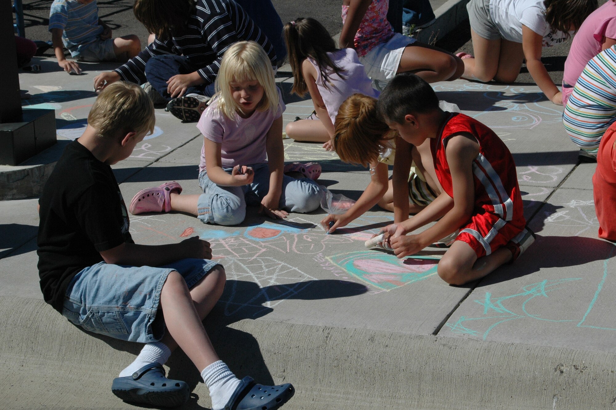 Clockwise, Little Warriors Blaine, 8, Morgan, 7, Summer, 7, and Darian, 6, work together on their chalk art project.  (U.S. Air Force photo / Valerie Mullett)