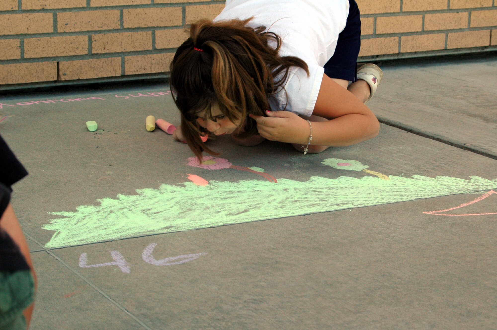 Little Warrior Emily, 8, blows off the excess chalk dust from her artwork she titled “Montana Summer.” (U.S. Air Force photo / Valerie Mullett)