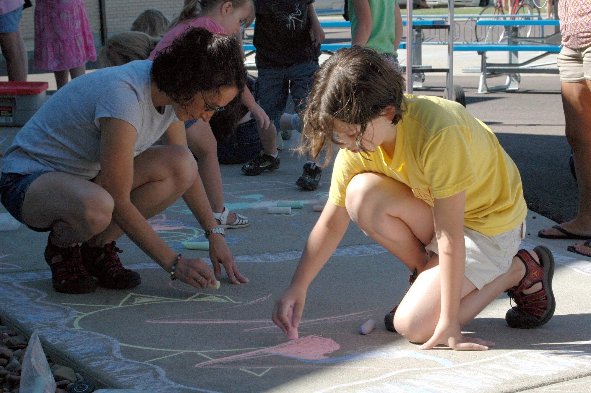 Little Warrior Danielle, 10, and her mom, Anne, team up on a chalk art creation during the Youth Program Center’s annual Chalk It Up! competition Wednesday. (U.S. Air Force photo / Valerie Mullett)