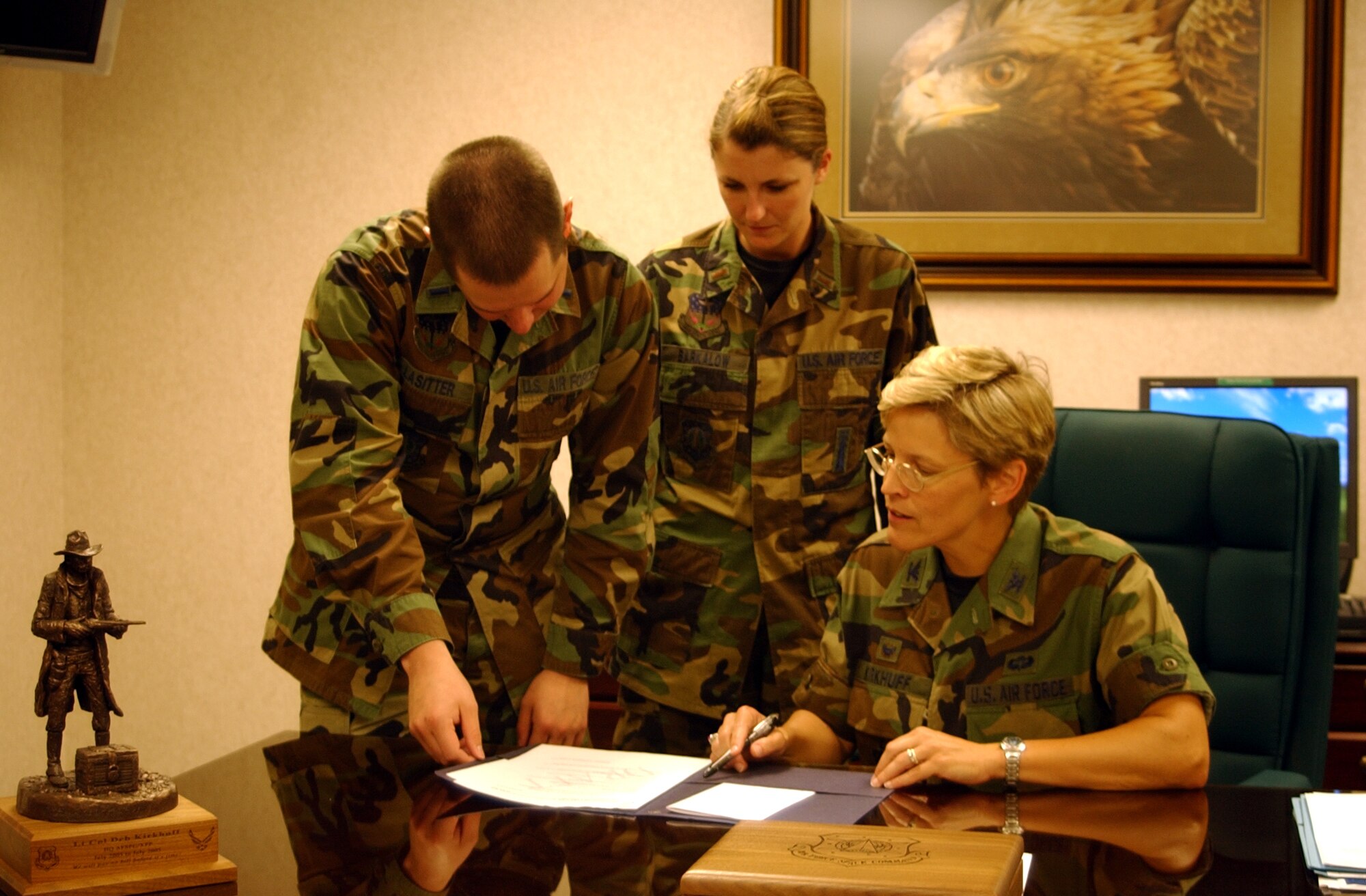Col. Deborah Kirkhuff, 341st Maint-enance Group commander, signs off on group operating instructions as 1st Lt. Jeffrey Lasitter, 341st MXG excecutive officer, and 2nd Lt. Allison Barkalow, 341st Maintenance Operations Squa-dron officer in charge of team training, look on.
