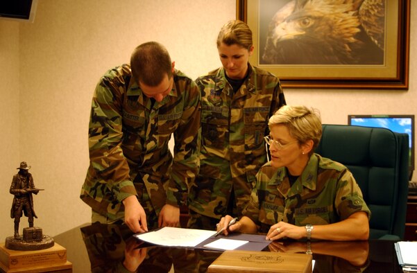 Col. Deborah Kirkhuff, 341st Maint-enance Group commander, signs off on group operating instructions as 1st Lt. Jeffrey Lasitter, 341st MXG excecutive officer, and 2nd Lt. Allison Barkalow, 341st Maintenance Operations Squa-dron officer in charge of team training, look on.