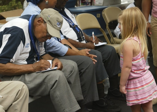 Leroy Eley, an origanal member of the Tuskegee Airmen, signs an autograph for a young admirer at the Air Force "Heritage to Horizons" event at Six Flags Over Georgia. (U.S. Air Force photo/Don Peek)