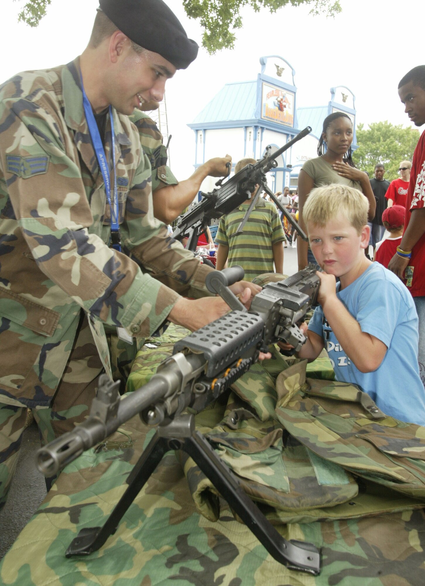 Senior Airman Brenton Hinkle from the 94th Security Forces Squadron assists Landon Sample with one of the weapons displayed at the Security Police vanue at Six Flags theme park on the 7th of July. (U.S. Air Force photo/Don Peek)