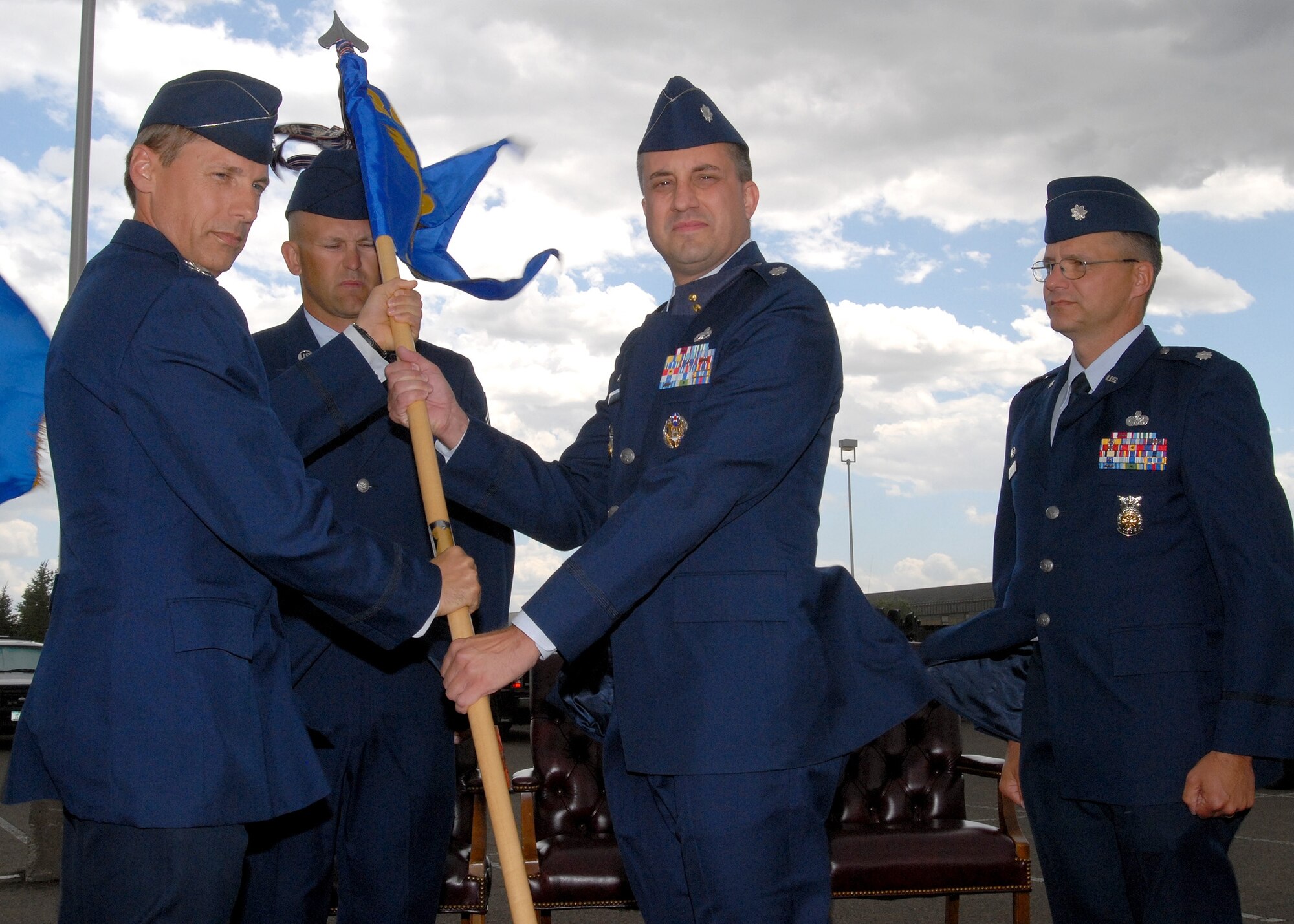 Lt. Col. Timothy Dodge accepts the guidon for the 341st Civil Engineer Squadron from Col. Roderick Davis, 341st Mission Support Group commander, during a change of command ceremony Monday at the Grizzly Bend Club. Outgoing 341st CES commander, Lt. Col. Daniel Costello, looks on. (U.S. Air Force photo / John Turner)