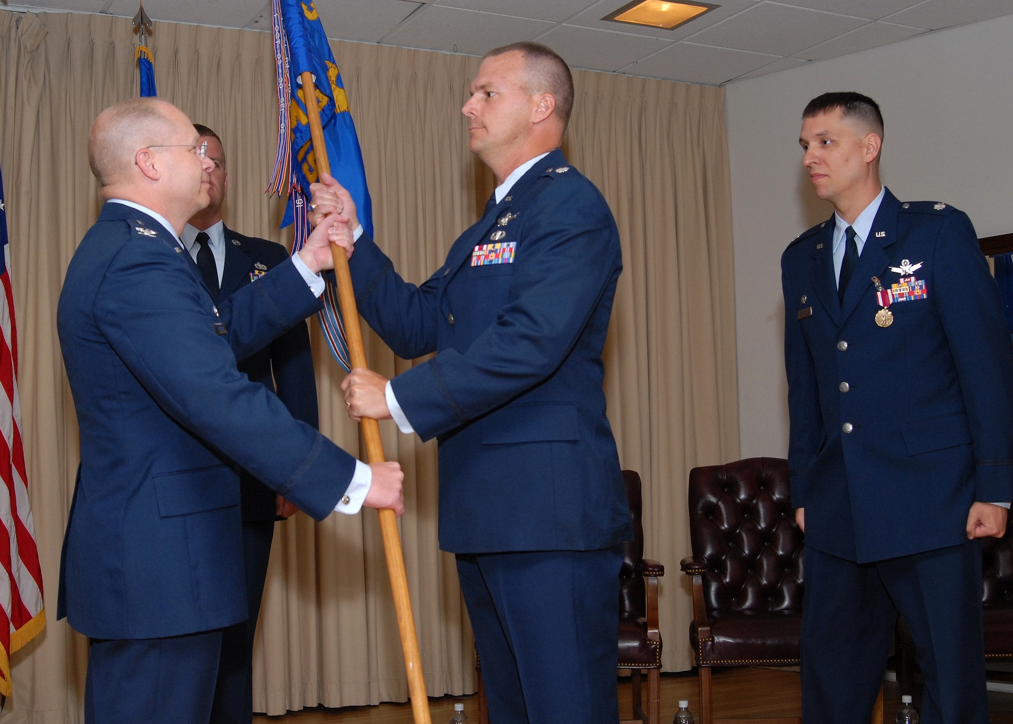 Lt. Col. David Stone accepts the guidon for the 10th Missile Squadron from Col. David Durgan, 341st Operations Group commander, during a change of command ceremony July 6 at the Grizzly Bend Club. Outgoing 10th MS commander, Lt. Col. Scott Edwards, looks on. (U.S. Air Force photo / John Turner)