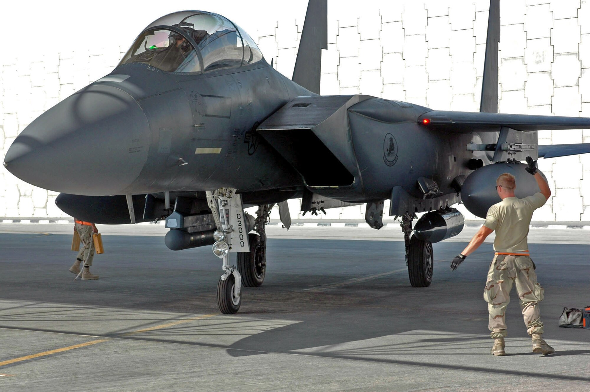 A crew chief marshals an F-15E Strike Eagle at a base in Southwest Asia.  The fighter had just returned from a close-air-support mission.  (U.S. Air Force photo.)
