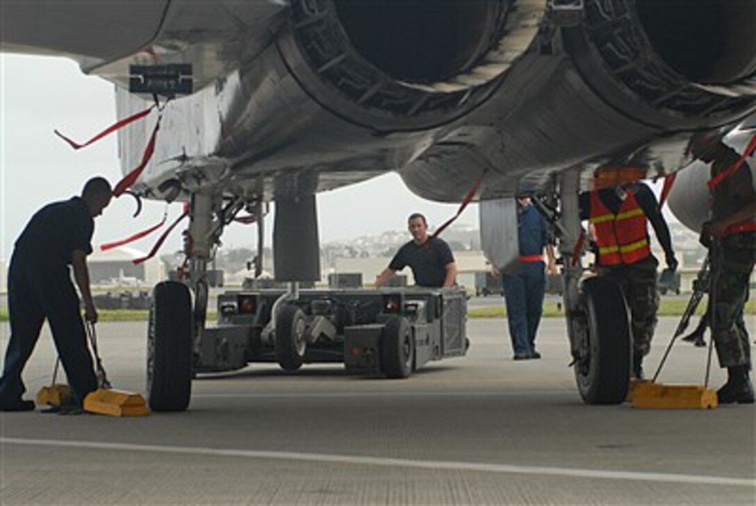 U.S. Air Force Staff Sgt. Justin Farr (center) drives an aircraft handler to place an F-15 Eagle in a protective aircraft shelter in preparation for Typhoon Man-Yi, July 12, at Kadena Air Base, Japan. The first typhoon of the season is expected to hit Okinawa, July 13. 