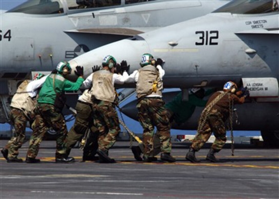 Navy flight deck crewman push an F/A-18C Hornet into post-flight position on the flight deck of the aircraft carrier USS Dwight D. Eisenhower (CVN 69) as the ship operates in the Atlantic Ocean on July 9, 2007.  The ship is underway in the Atlantic to conduct carrier qualifications.  