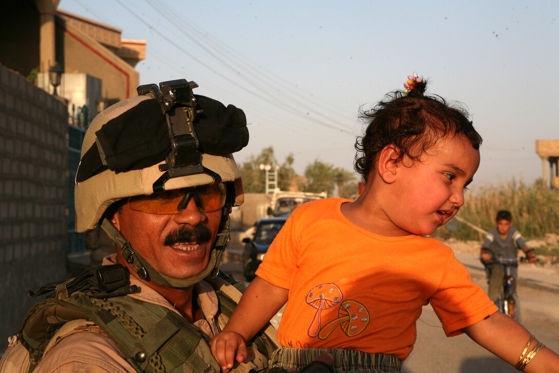 Ramadi Iraq (July 14, 2007) -- Iraqi Army Sgt. Maj. Abbas Abud Kadin, the senior enlisted man of the Iraqi Scout Sniper Platoon holds a child during a foot patrol through the ghetto of the of Ramadi.  The patrol was trying to find out what the citizens of Ramadi needed to make their neighborhoods a better place to live.