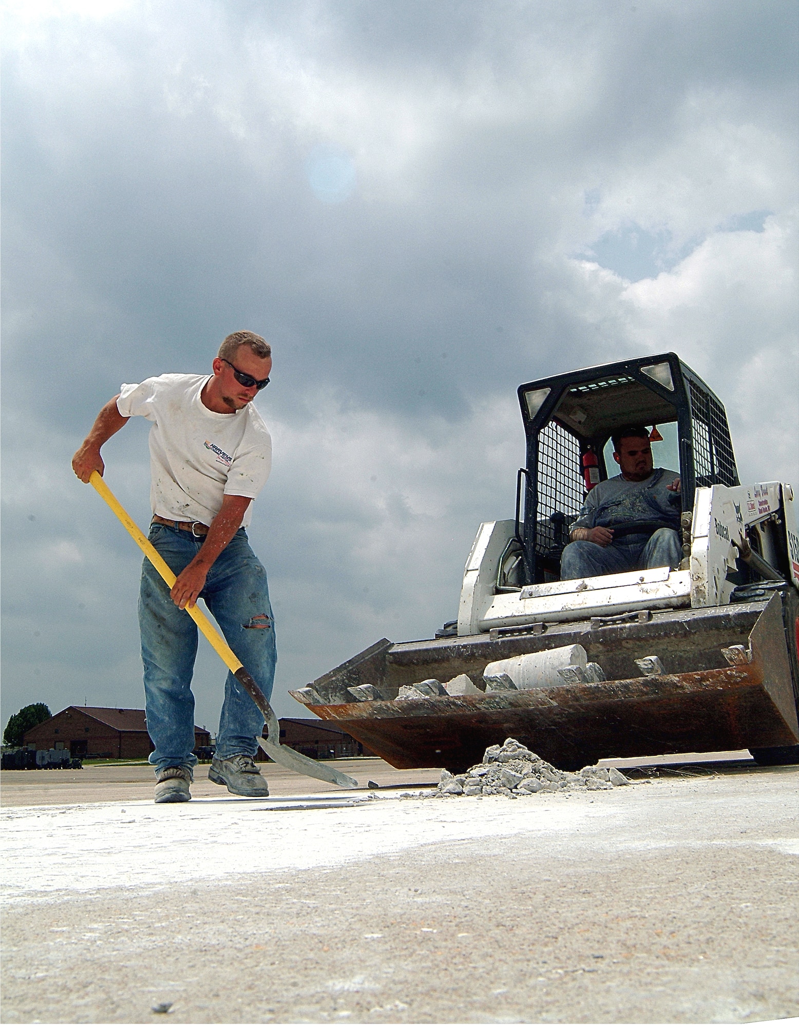 Jimmy Coffland shovels broken concrete into the bucket of a front-end loader driven by Dustin Draper while working on a project to replace tie down and grounding points on the 442nd Fighter Wing's A-10 parking ramp at Whiteman Air Force Base, Mo.  Both work for Larry Brandt Construction Company, which was contracted to do the work.  This is one of 14 construction projects taking place to build up the wing after it gained nine A-10s and additional people under the 2006 Base Re-alignment and Closure process.  (U.S. Air Force photo/Master Sgt. William Huntington)