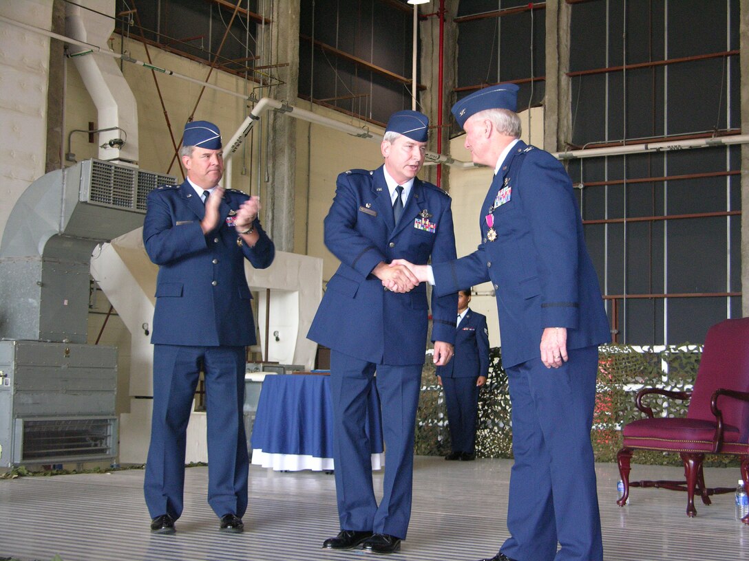 Col. Paul J. Sykes, former wing commander of the 916 ARW shakes hands with new commander, Col. Fritz Linsenmeyer. Maj. Gen. Robert Duignan stands to the left congratulating both. The change of command for this Air Force Reserve was held on July 14. (U.S. Air Force Photo/ Staff Sgt. Scott Mathews)