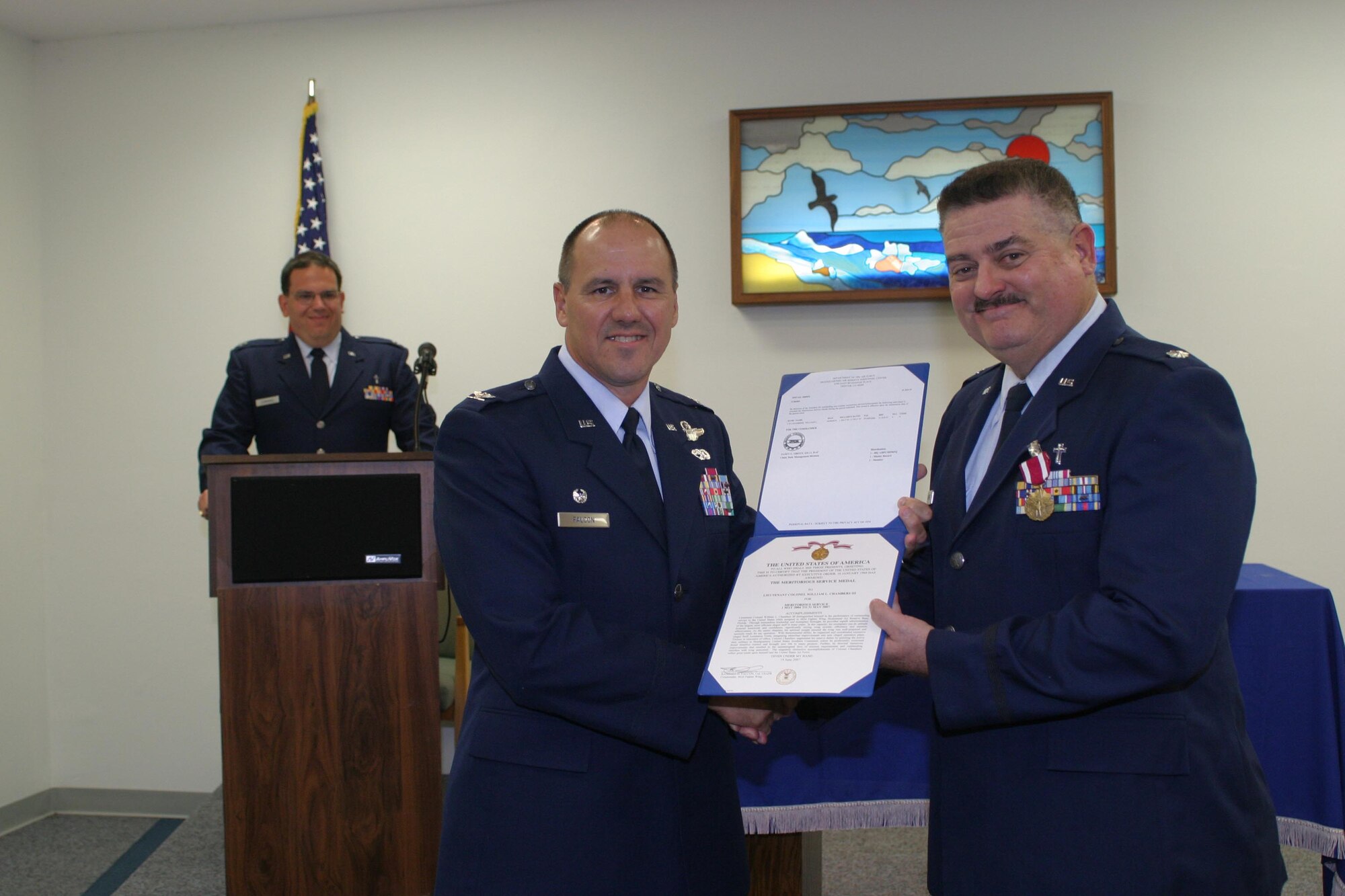 The Meritorious Service Medal is presented to Chaplain (Lt. Col.) William Chambers by 482nd Fighter Wing Commander Col. Randy Falcon July 14.  Chaplain Chambers is leaving the 482nd FW after more than 18 years of service to the wing. 
Chaplain (Capt.) Vincent Cummings (in the background) officiated the departure ceremony and is assuming the duties of 482nd FW chaplain. (U.S. Air Force photo/Tech. Sgt. Paul Dean)
