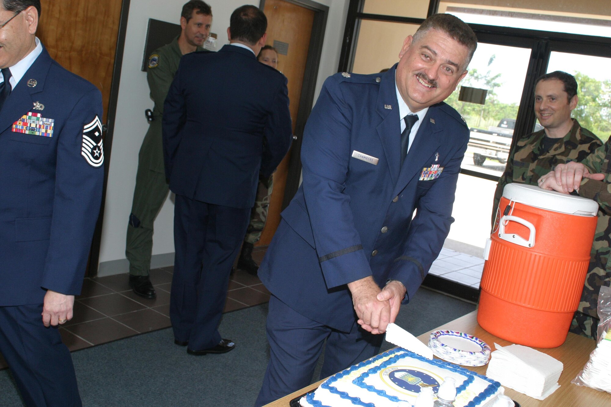 Chaplain (Lt. Col.) William Chambers prepares to slice the cake at his departure ceremony July 14. Chaplain Chambers is moving on to serve as SOUTHCOM Garrison Chaplain and leaves with a reminder to all airmen: Train as if every day were the real thing. Only this way can airmen avoid the necessity of “shifting gears” when the real world turns real, he said. (U.S. Air Force photo/Tech. Sgt. Paul Dean)