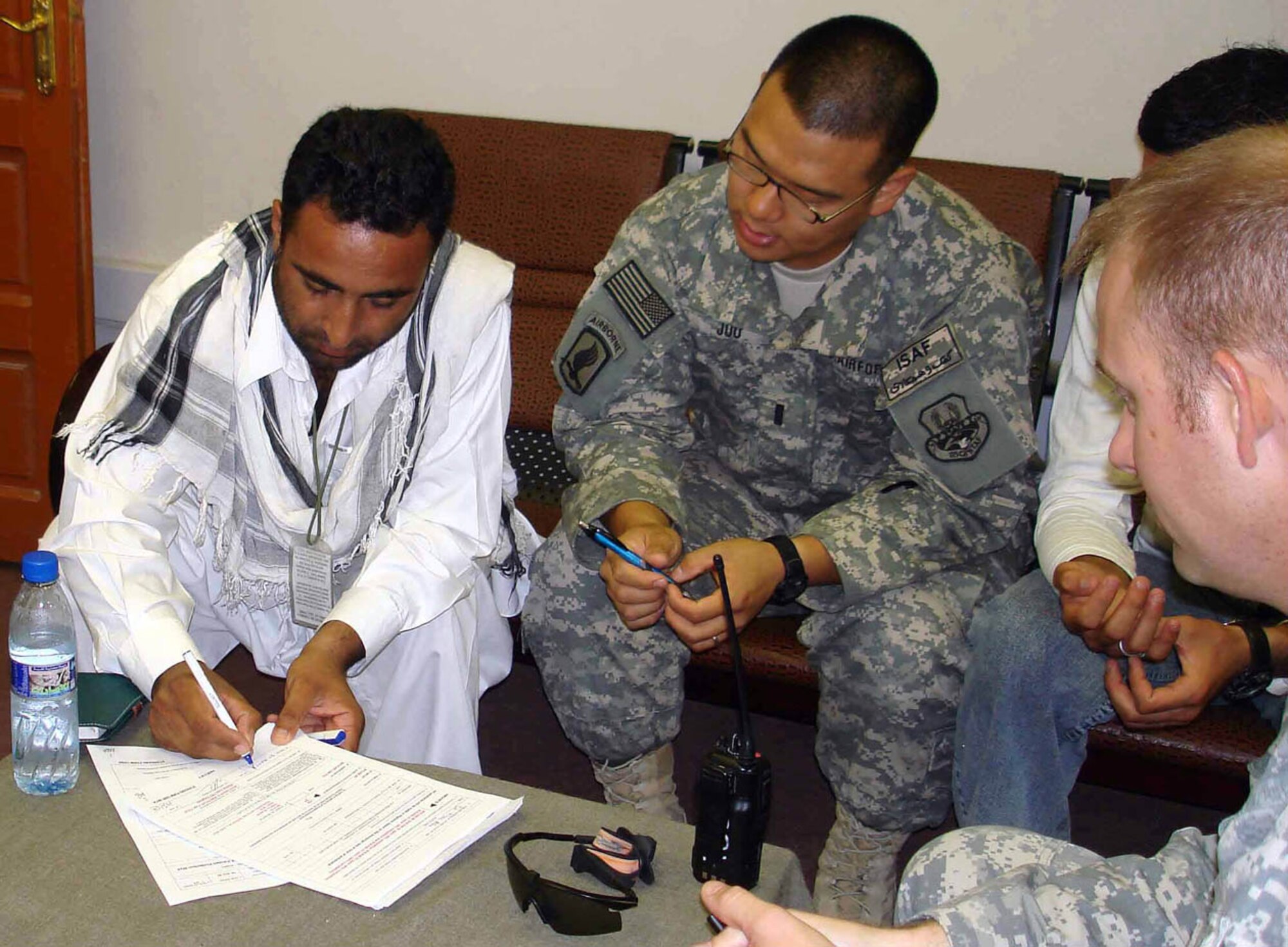 Air Force 1st Lt. Peter Joo (center), Mehtar Lam Provincial Reconstruction Team engineer and Air Force Capt. Matthew Brennan (right), PRT engineer look on as Dr. Noor Ali, President, New Sahak Construction Company, signs the contract to begin construction on a flood retaining wall.  The wall will be built in Kandah Village and protect people and property from flooding and land erosion. (U.S. Air Force photo by Lt. Col. Robert Ricci)